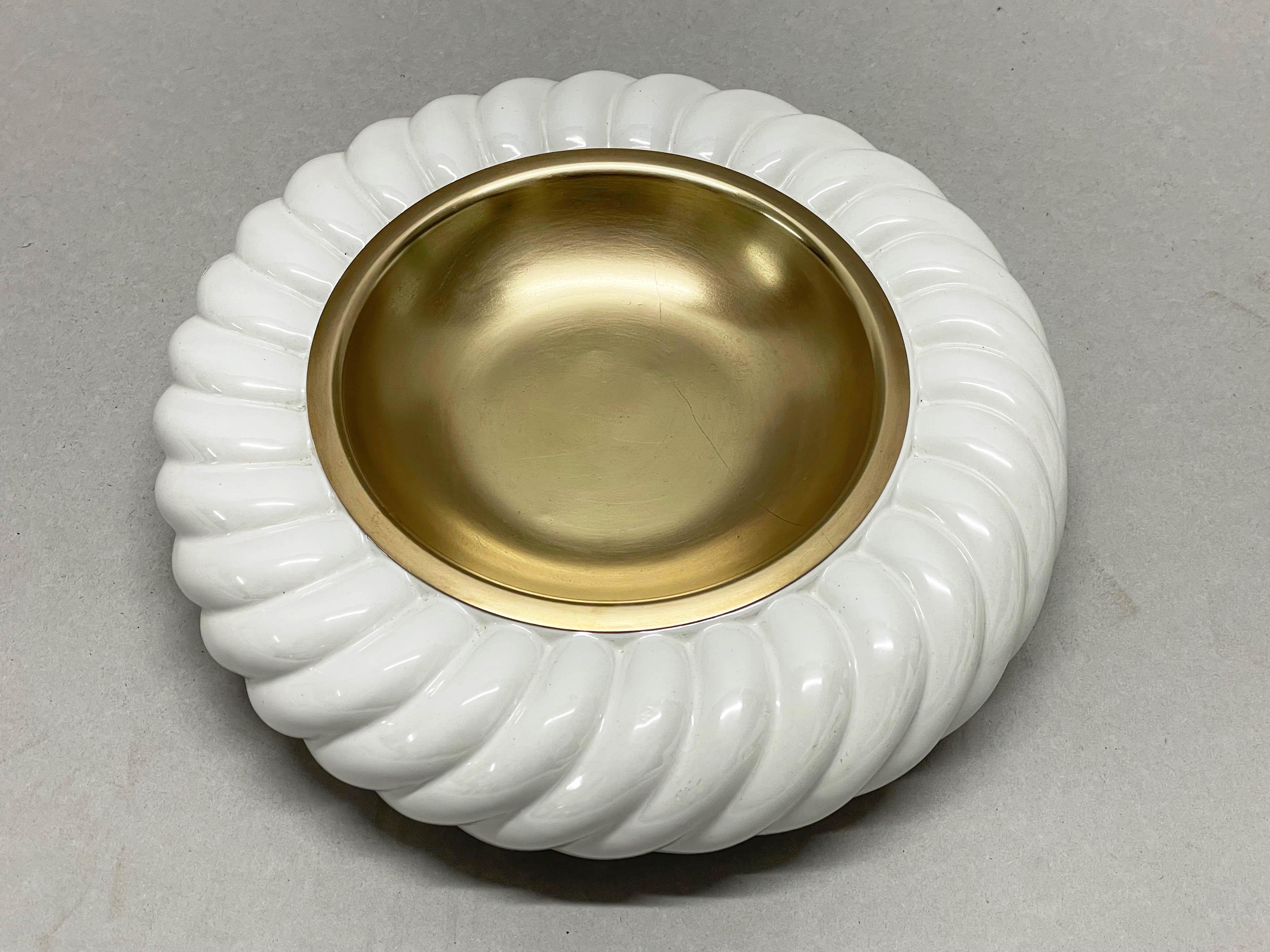 Incredible Mid-Century Modern white ceramic and brass ashtray. This fantastic piece was designed by Tommaso Barbi and produced by B. Ceramiche in the late 1960s in Italy.

The manufacturer's brand stamp is at the bottom of the item while on the