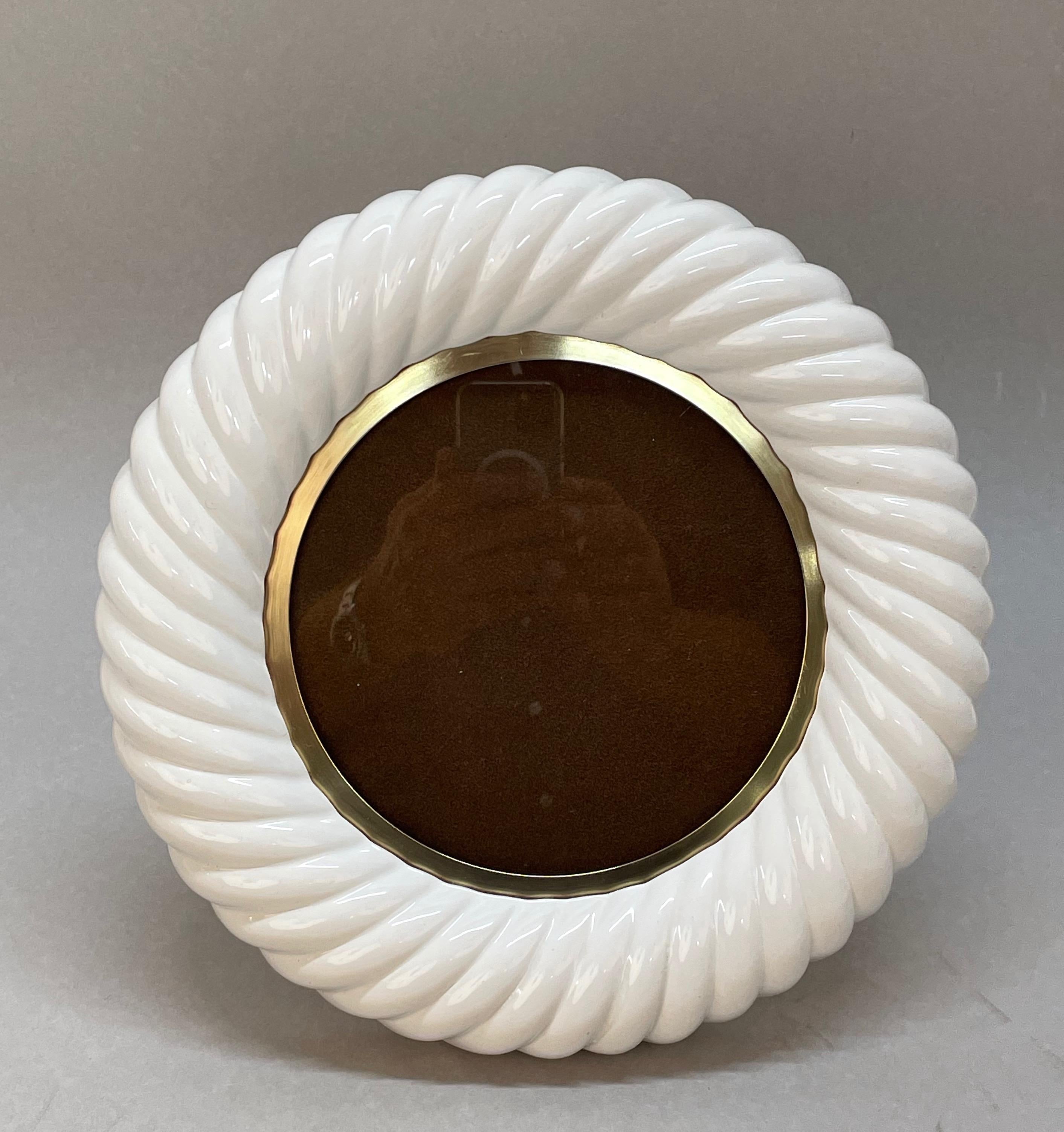 Incredible mid-century frame in white ceramic and brass. This wonderful object was designed by Tommaso Barbi, as you can see his signature on the back, in Italy in the 70s.

This piece is unique for the fine artisanal work on the white ceramic in