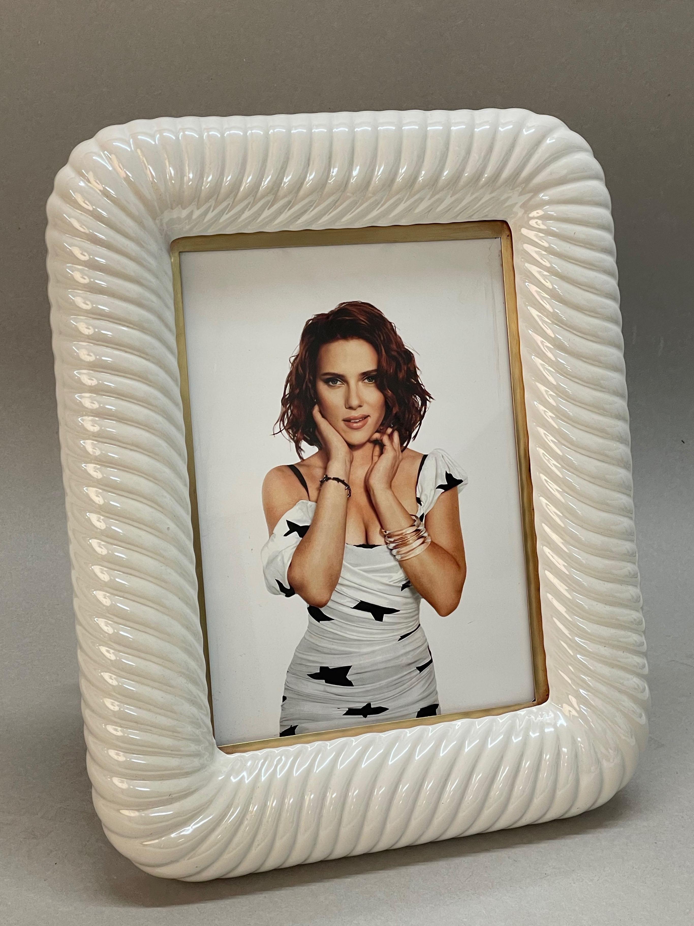 Incredible mid-century frame in white ceramic and brass. This wonderful object was designed by Tommaso Barbi, as you can see his signature on the back, in Italy in the 70s.

This piece is unique for the Fine craftsmanship on the white ceramic in