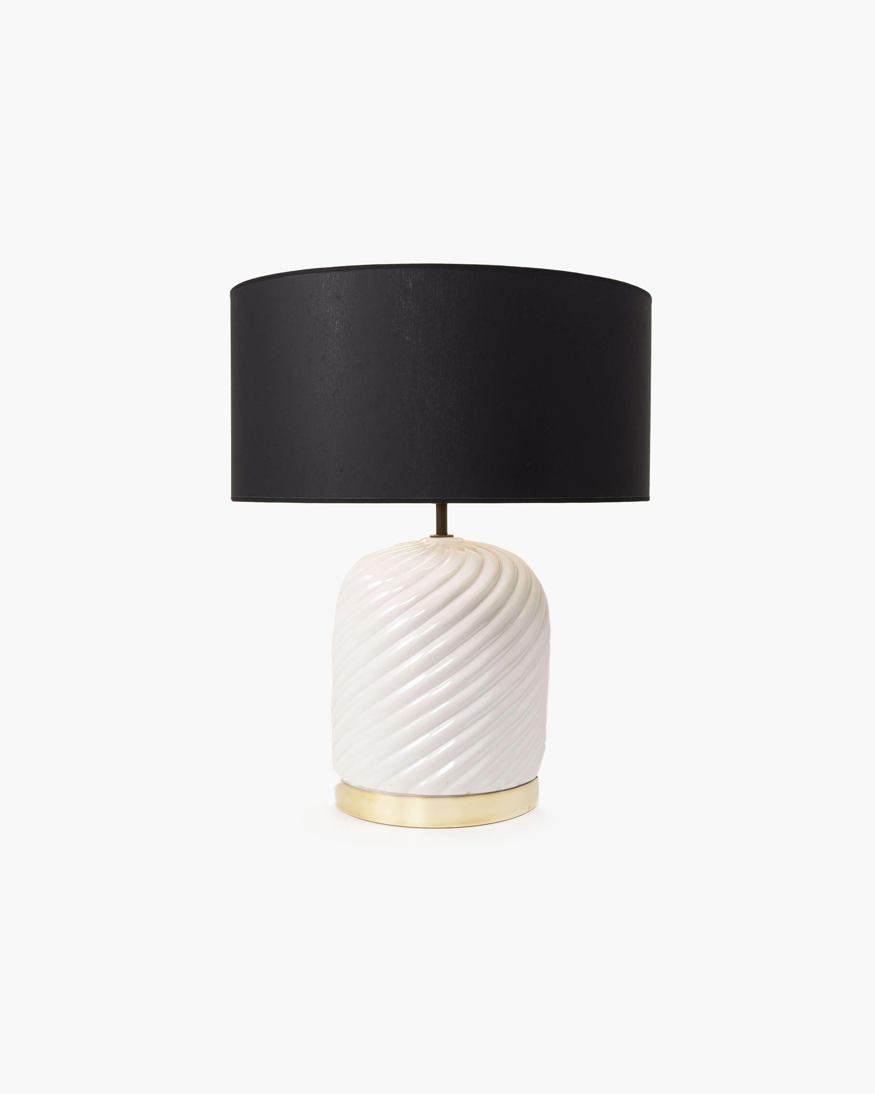 This elegant pair of table lamps by Italian designer Tommaso Barbi features an ivory-colored ceramic base with horizontal spiral shaping grounded by a brass ring. The almost sculptural form of Barbi’s table lamp is an excellent piece to elevate and