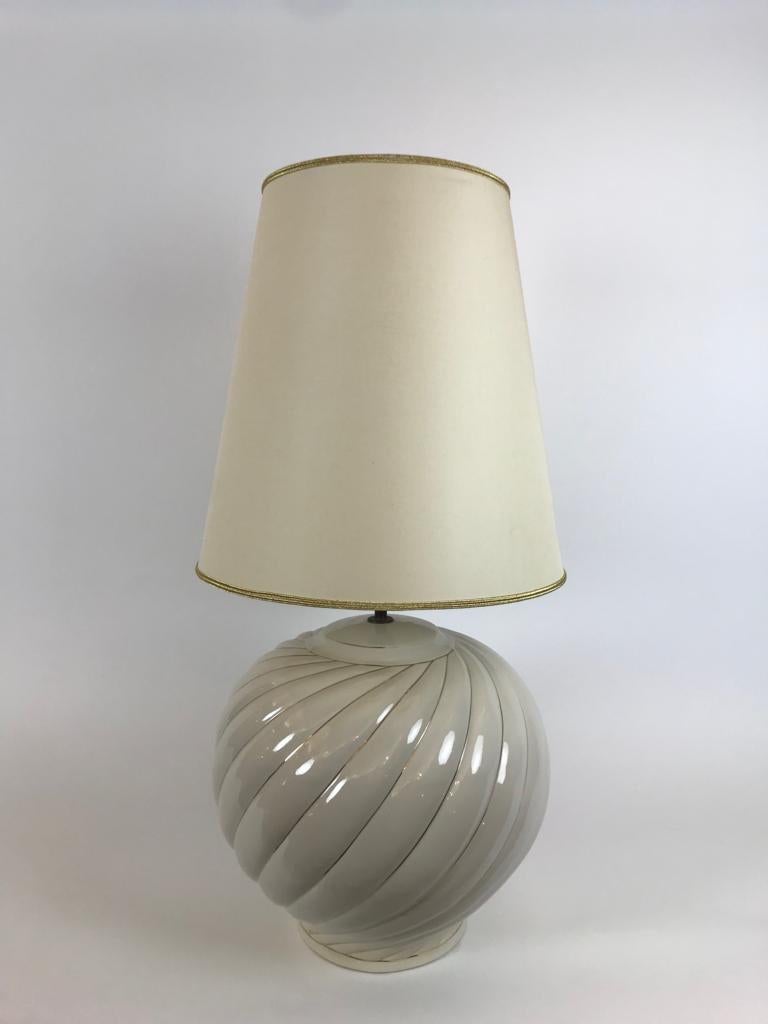 A wonderful pair of cream ceramic table lamps designed and produced by Tommaso Barbi in Italy in the 1970s. They have a ceramic base with a spiral pattern with gold detailing and a cream and gold original lampshade. They are signed on the bottom.