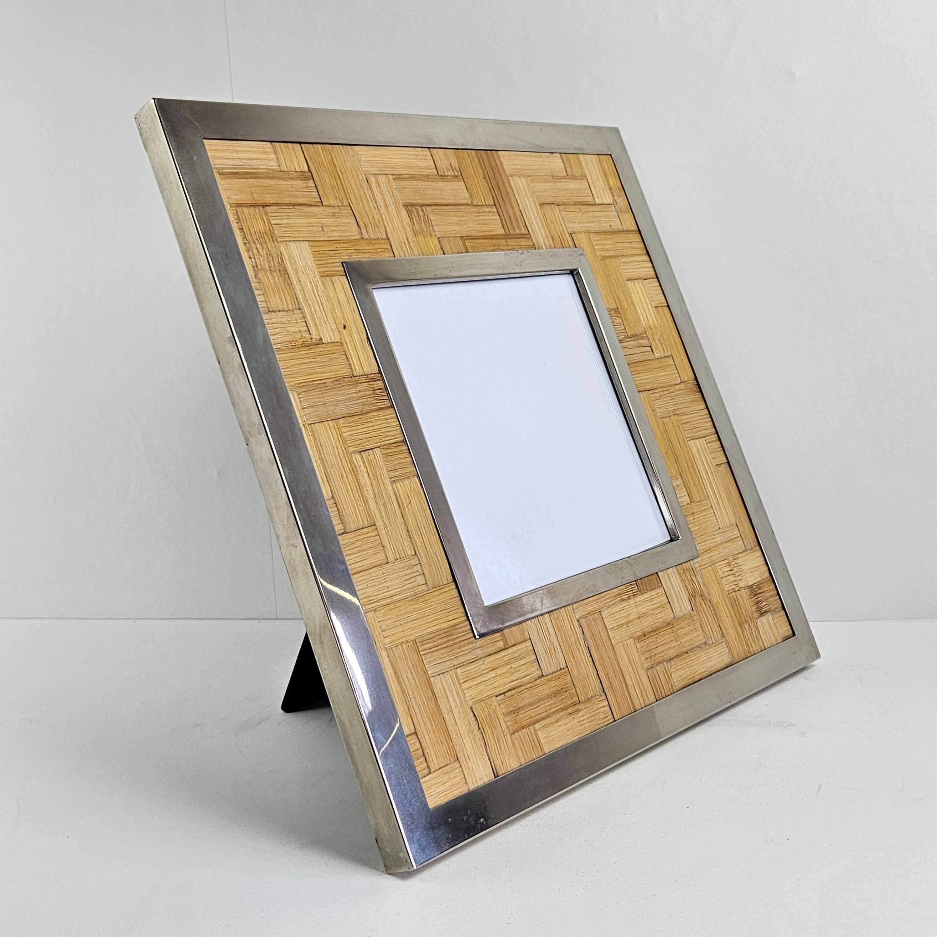 Lovely and very decorative desk picture frame from the beginning of the 80's.
Fabricated by Tommaso Barbi (TB), Italy.

A carefully crafted square silver plated frame with rattan decoration.
It is fitted at the reverse with one hinged retractable