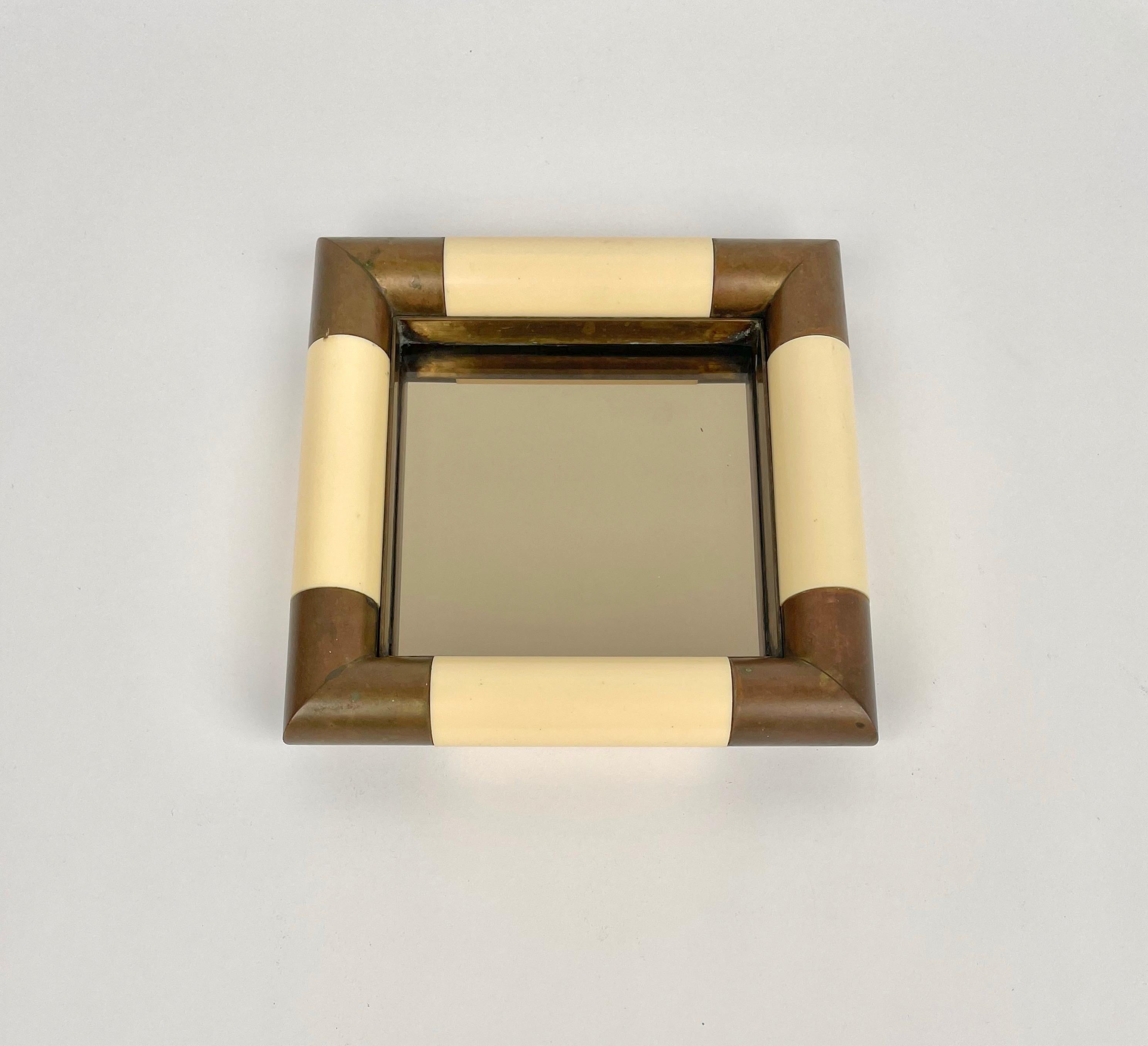 Squared vide-poche in bronzed mirror with brass corners and frame in ivory-colored plastic material by the Italian designer Tommaso Barbi. 

Made in Italy in the 1970s.