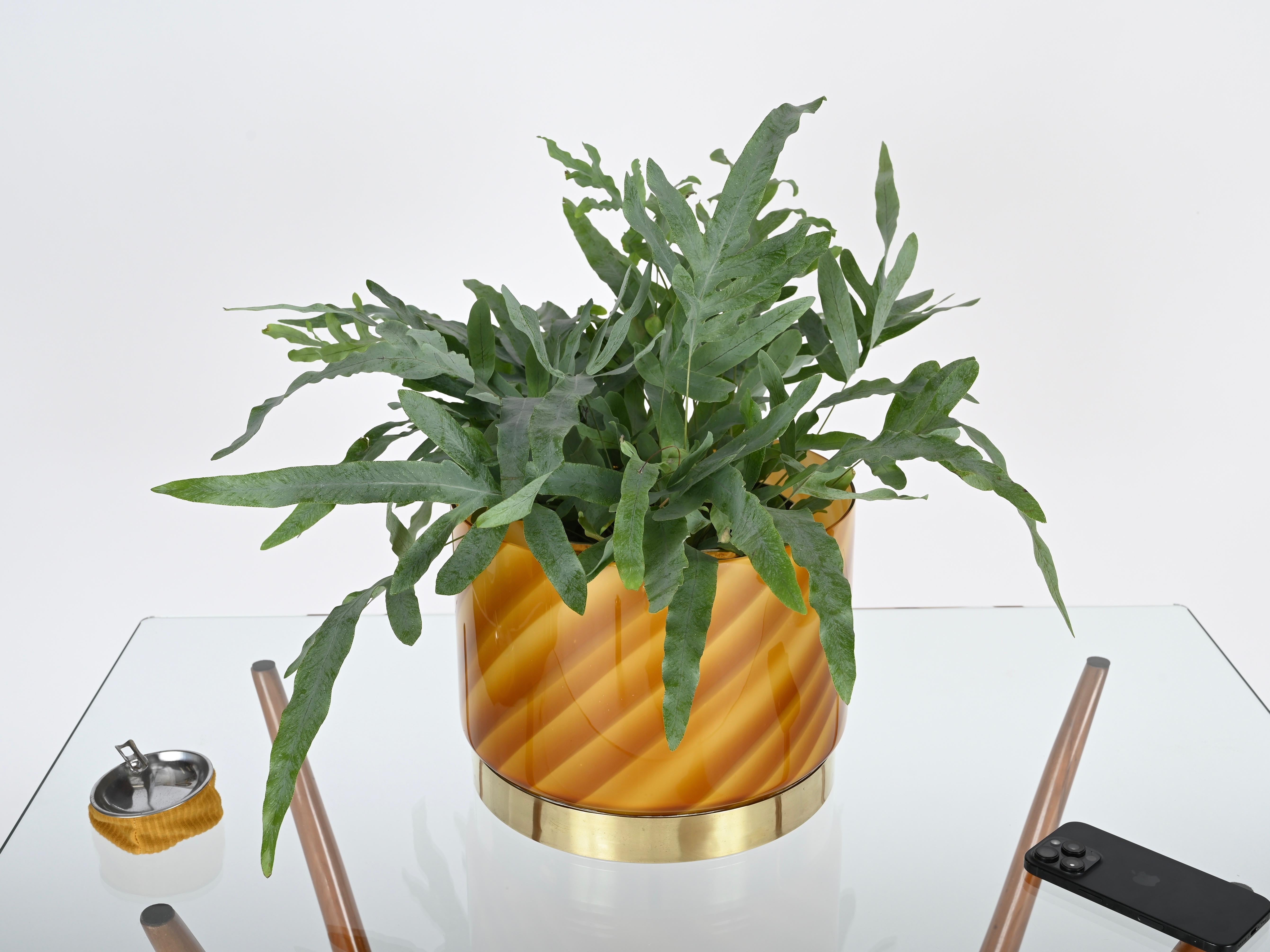 Splendid mid-century cachepot in Murano glass and brass. This incredibly elegant and unique piece was designed by Tommaso Barbi in Italy during the 1960s and is signed inside. 

In fabulous condition, with no chips or cracks. This refined decorative