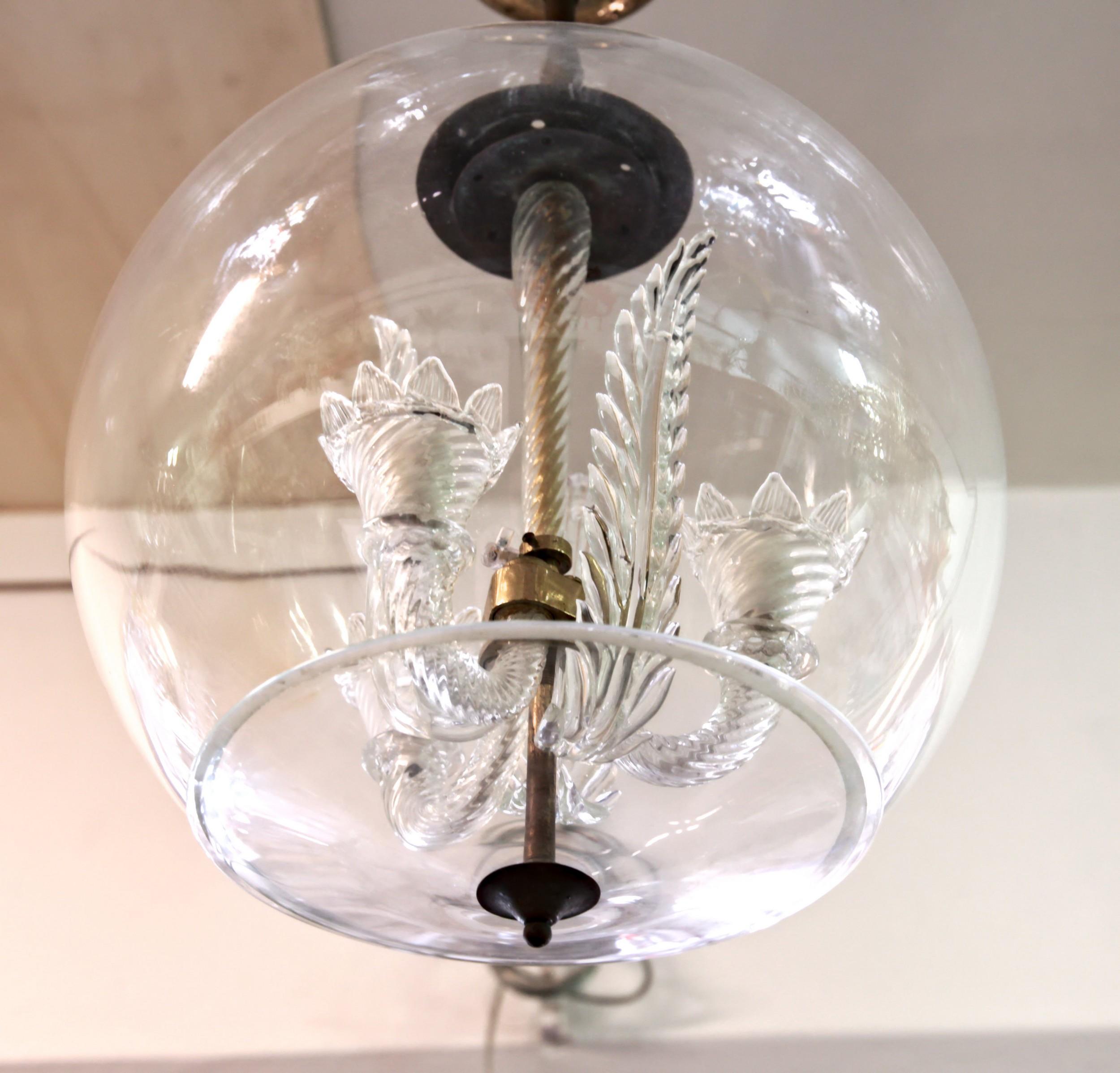 Historical Venini piece created under former director Tommaso Buzzi.
Small glass chandelier with 3 leaves and brass hardware encased in a glass sphere with a lower lid.

Collector's museum piece. 

Venini blue catalog figure 138,

Reference
Venini.
