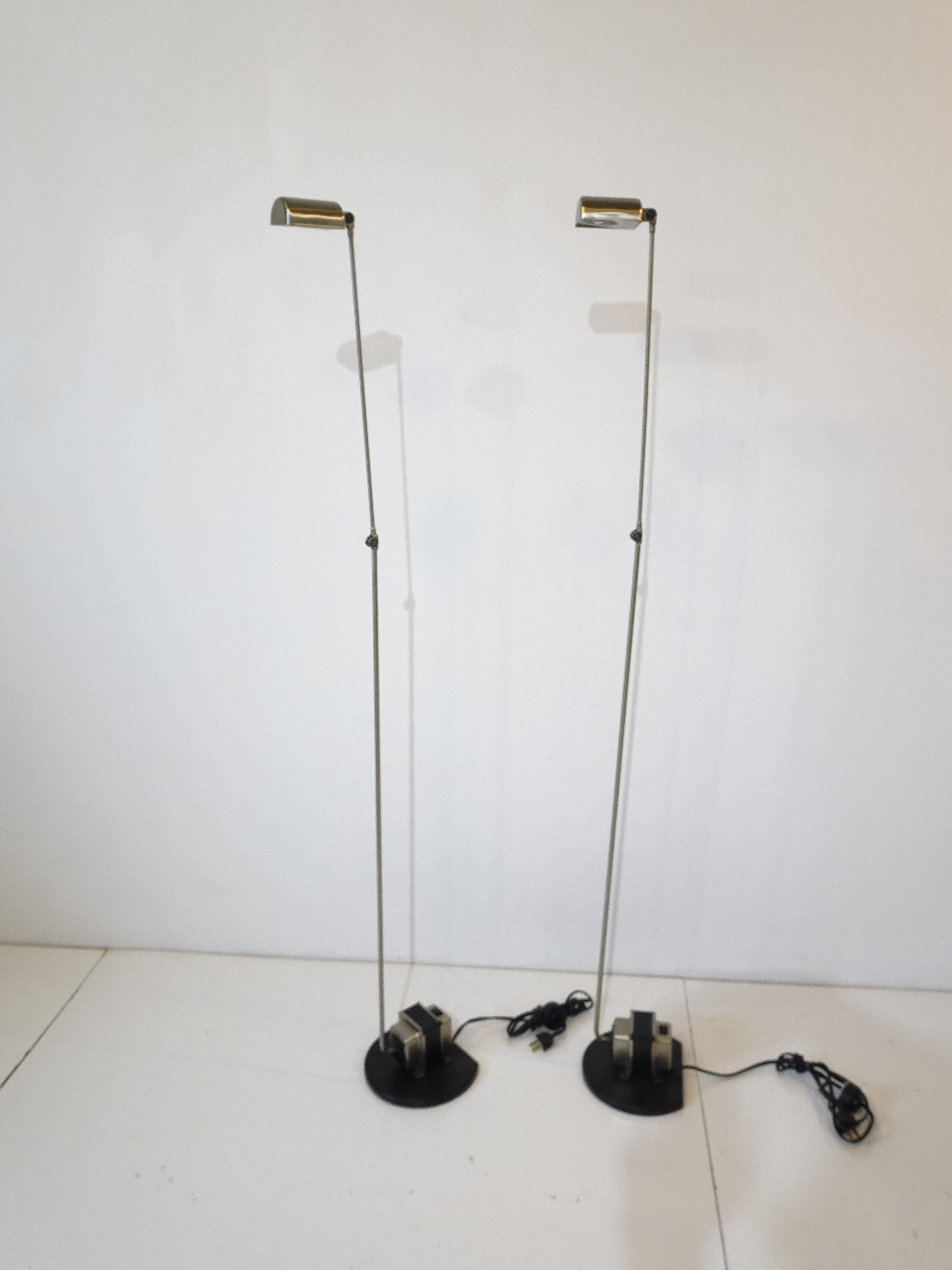 A pair of brushed nickel toned Italian Daphine Terra floor lamps with exposed transformer and black cast iron bases having articulating 360 degree arms . The stem of the light in the center bends and there's a ball in the base so the stem can rotate