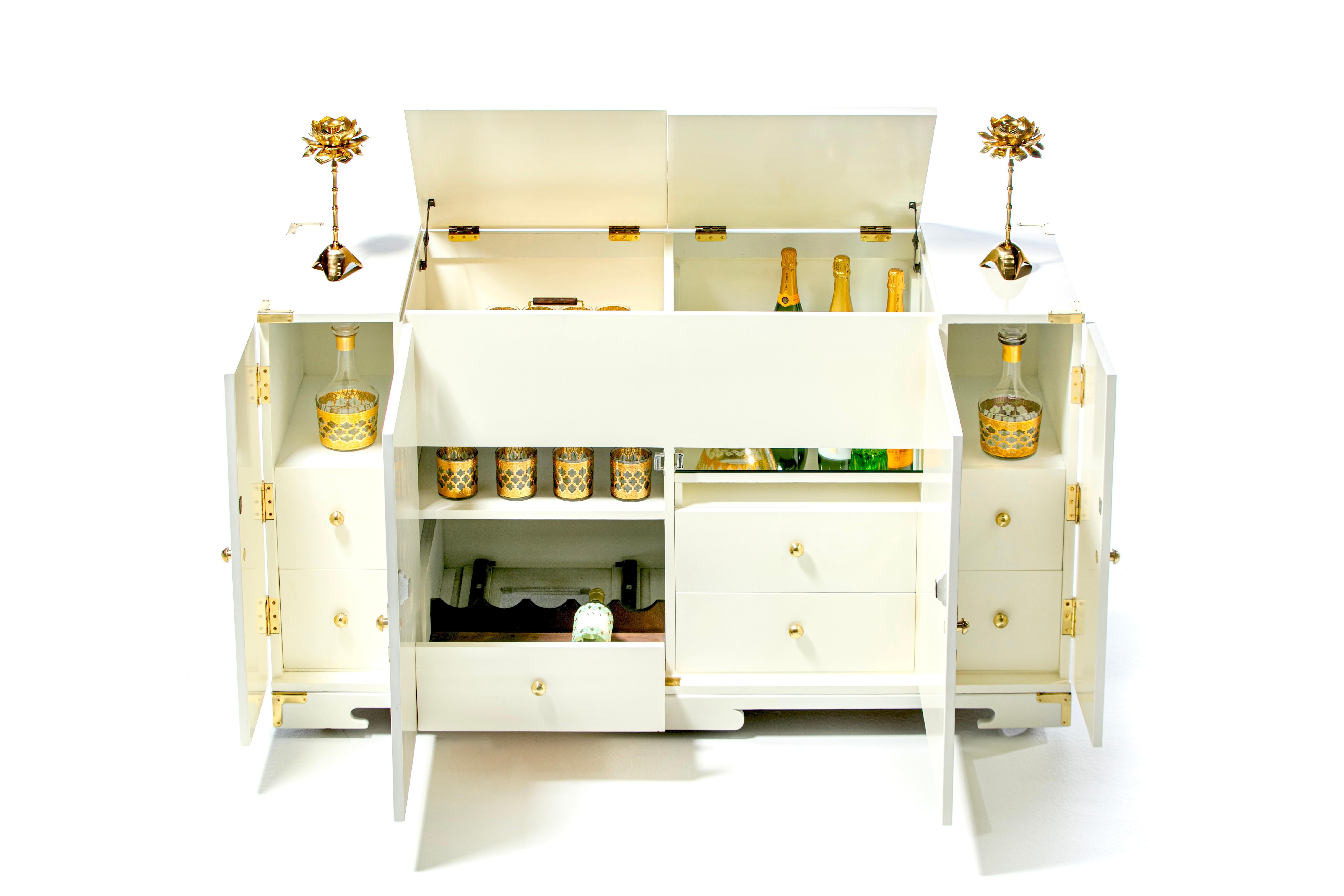 Glamorous Hollywood Regency Bar Cabinet attributed to Tommi Parzinger newly lacquered in white chocolate with polished original adorning brass hardware. Fully restored from top to bottom. Jewelry for your home or work space, this mid century bar