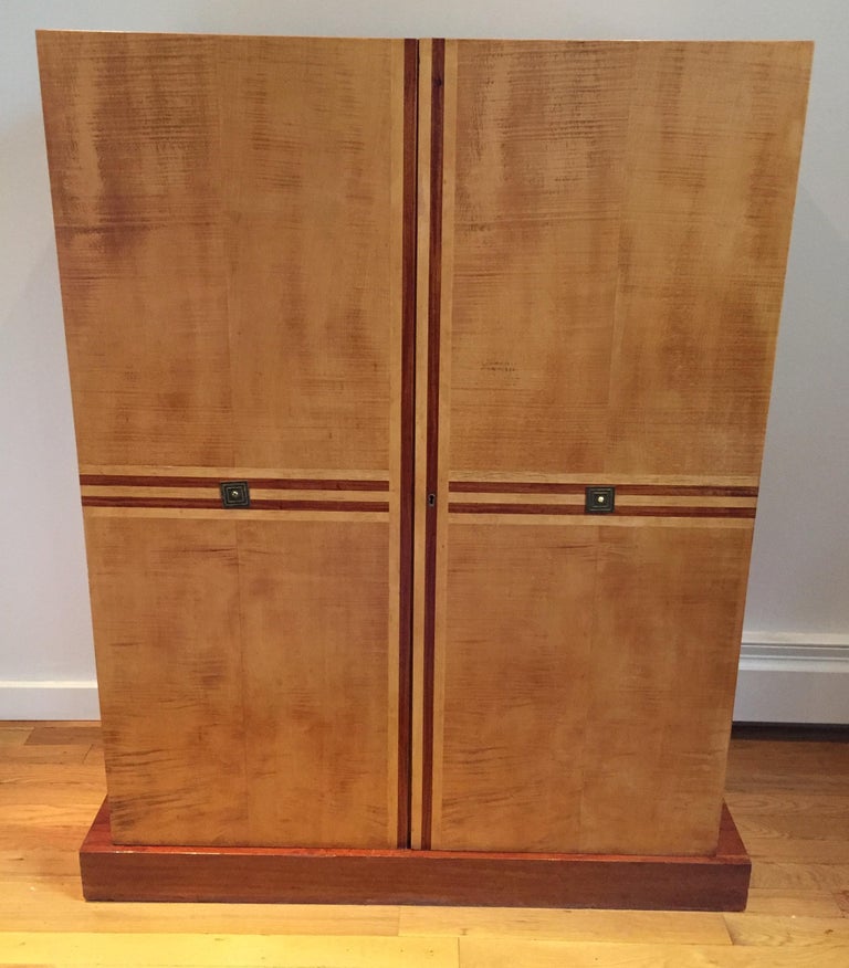 Figured birch cabinet on plinth with sexy mahogany inlay racing stripe. The interior is fitted with drawers and fixed shelves. From a Parzinger decorated Bergan County, NJ interior, circa 1950s, included in the Parzingers Originals catalog, model #