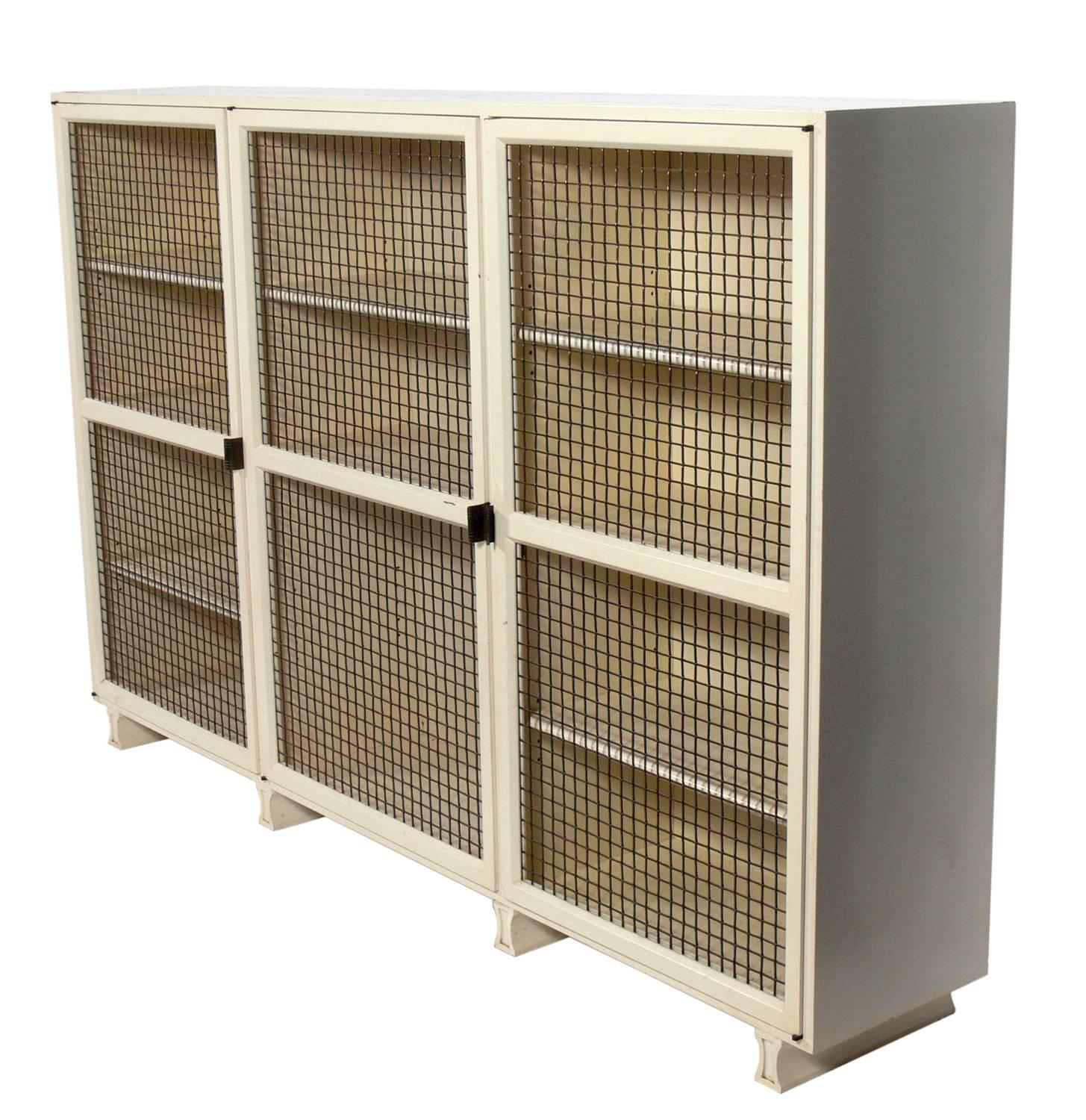 Elegant bookcase or vitrine, designed by Tommi Parzinger for Parzinger Originals, circa 1950s. This piece is a versatile size and can be used as a bookcase, vitrine, bar, or display case. It features three doors that open to reveal eight adjustable