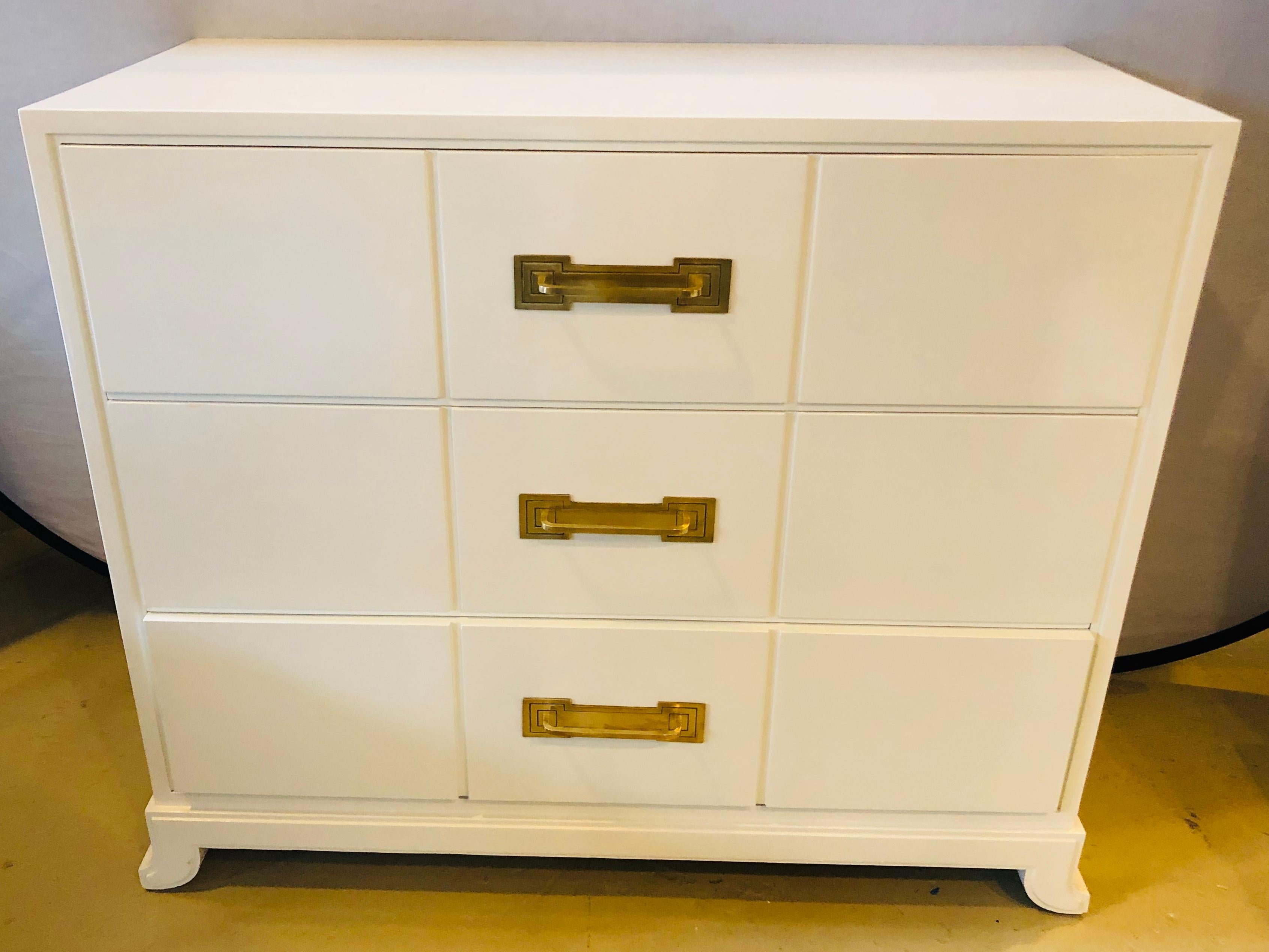 Tommi Parzinger / Charak modern white lacquered Hollywood Regency chest, nightstand or commode. This wonderfully decorative chest, dresser or nightstand has been professionally done over in a fine white lacquered finish. Having three drawers with