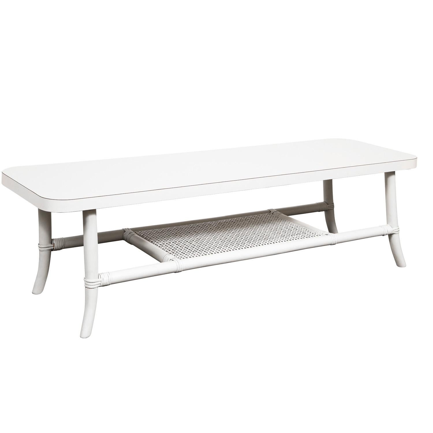 Elegant white lacquered coffee table with splaying legs, white laminate top and caned shelf by Tommi Parzinger for Willow and Reed, American 1950’s. Willow and Reed designed furniture ideal for enclosed porches or outdoor areas not exposed to the