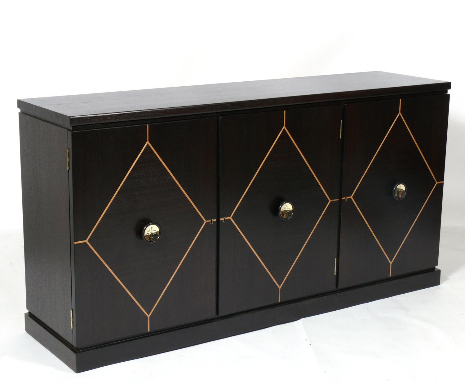 Elegant inlaid credenza, designed by Tommi Parzinger for Charak, American, circa 1950s. It offers a voluminous amount of storage, with the left and right doors opening to reveal large areas with adjustable shelving, and the center door opening to