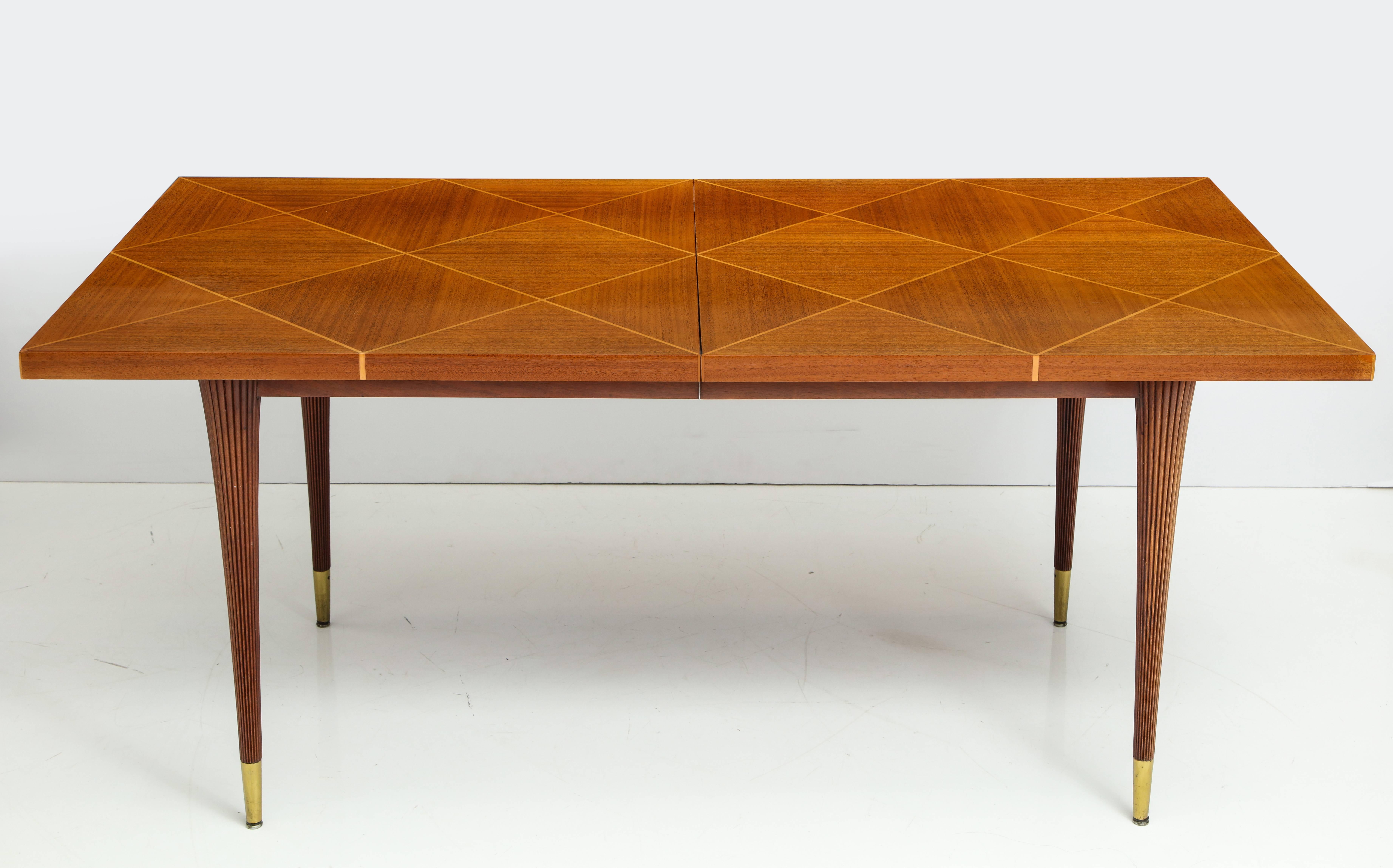 Elegant and classic dining table in bleached mahogany with a parquetry top with beech inlay and fluted tapering columnar legs with brass sabots. By Tommi Parzinger for Charak Modern, circa 1940s. Measures: Opens to 85