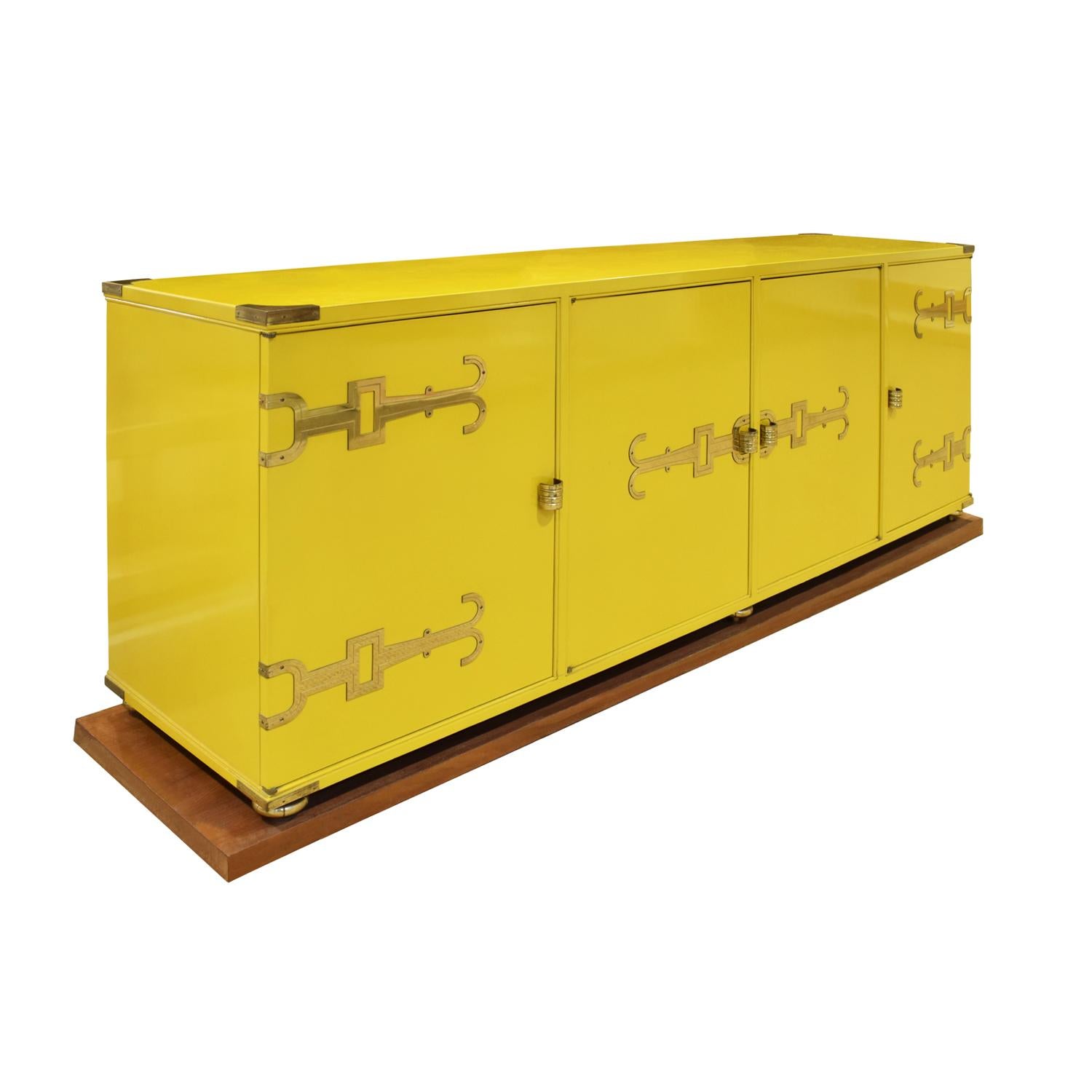 Exceptional credenza model #140 in yellow lacquer with iconic etched brass hardware, corner accents and sculptural ball feet which sit on a plinth base by Tommi Parzinger for Parzinger Originals, American 1950s. Since the lacquer is original and has
