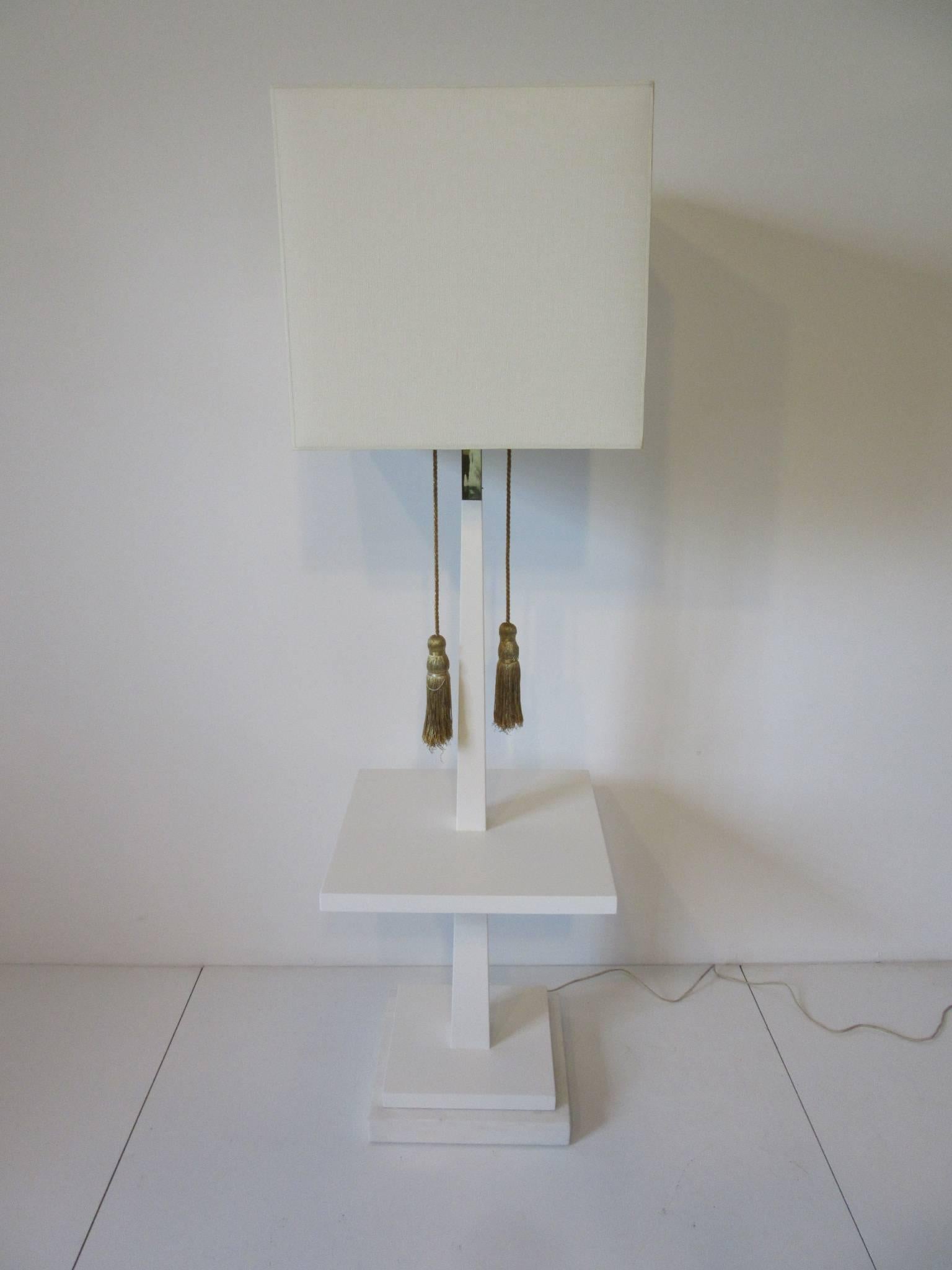 A very well crafted wooden floor lamp with intergraded table sitting on a piece of white Italian Carrera marble as the base . Retains it's original gold braded pulls and end tassels with an accent of brass to the center shaft . Retains the imprinted
