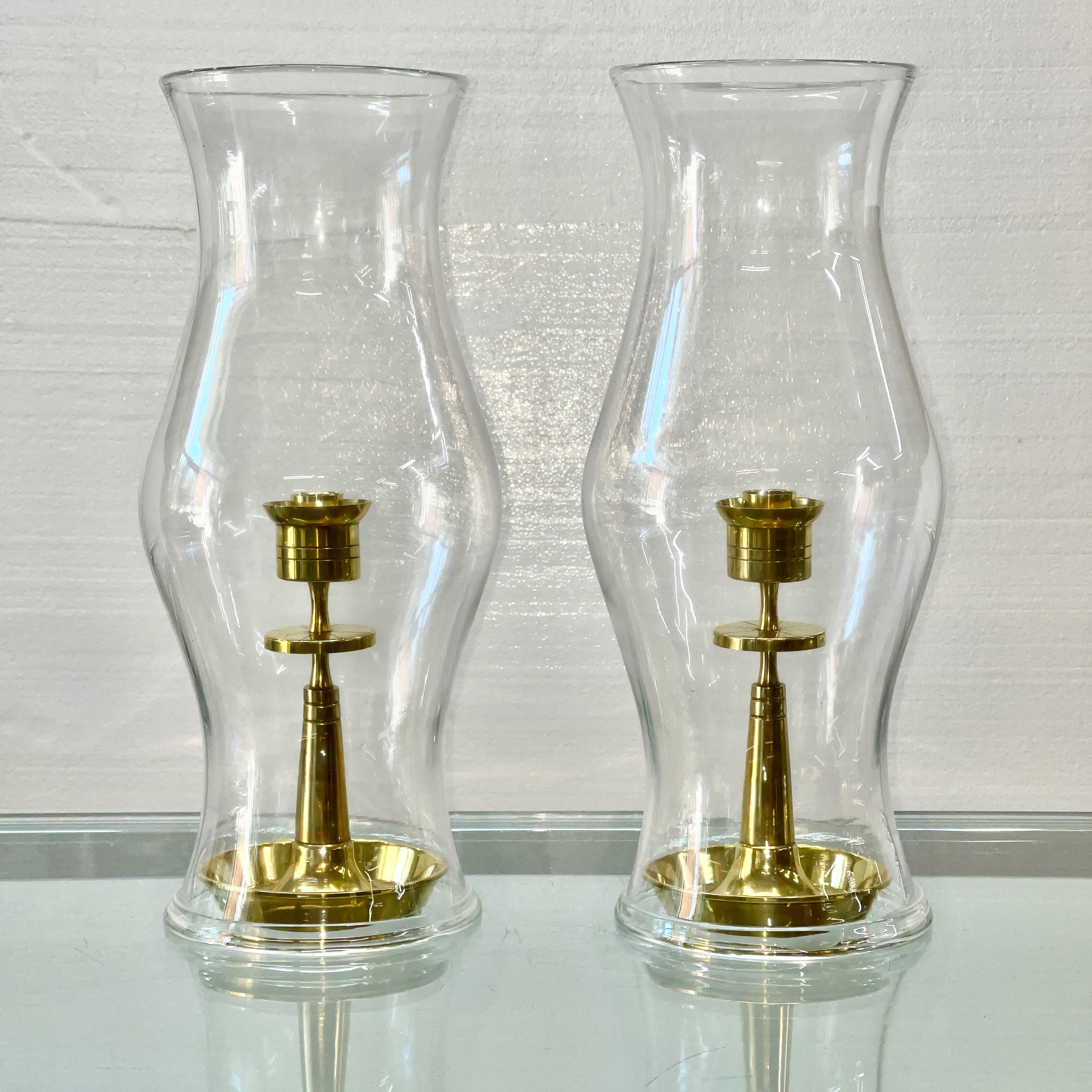 Pair of brass candle holders from Dorlyn Silversmiths' early 1950's brass ware collection designed by Tommi Parzinger including a pair of shaped hurricane glass shades.

Measures: Candle holders are 9.5