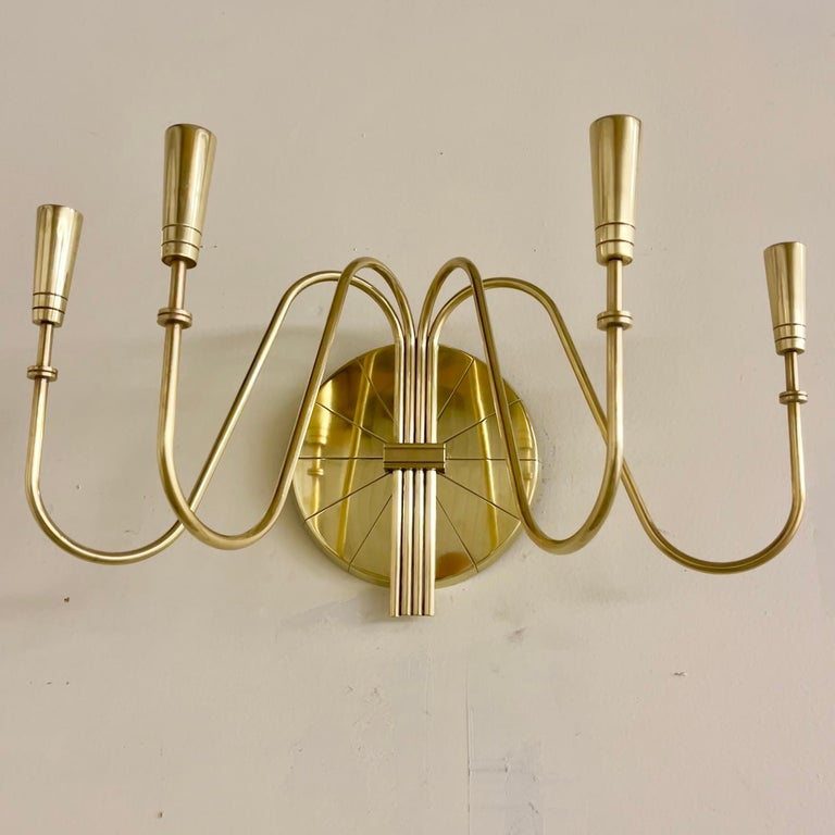 Grand scale wall mounted candle sconce with four branches designed by Tommi Parzinger for Dorlyn Silversmiths. 
This uncommonly seen candelabrum measures 21” wide x 10” high x 10” deep. Medallion 8” diameter. 
Signed on the back.
The brass arms