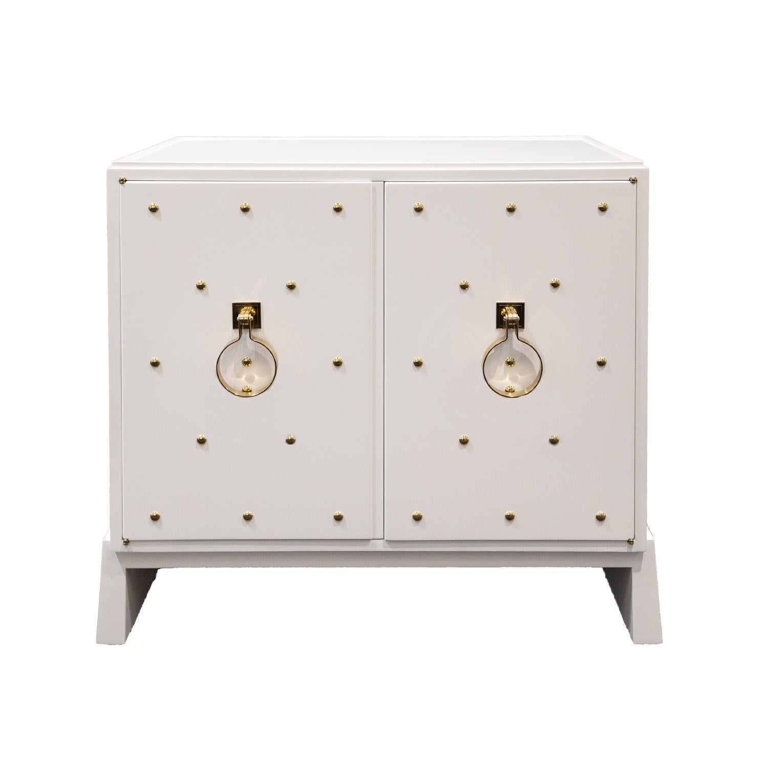 Iconic 2 door cabinet model 146 in white lacquer with brass studs, etched brass pulls, and inset milk glass top by Tommi Parzinger for Parzinger Originals 1950s (signed “Parzinger Originals” on inside of drawer). This beautiful cabinet exudes the