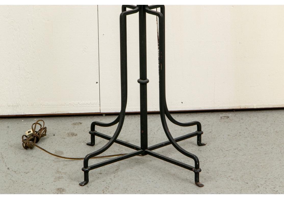 Designed by Tommi Parzinger for Parzinger Originals in the 1950s. A tall iron torchiere with four faux candles in antiqued finish. The standard with shaped details on the top, middle and lower parts. Mounted on a shaped criss-cross four legged