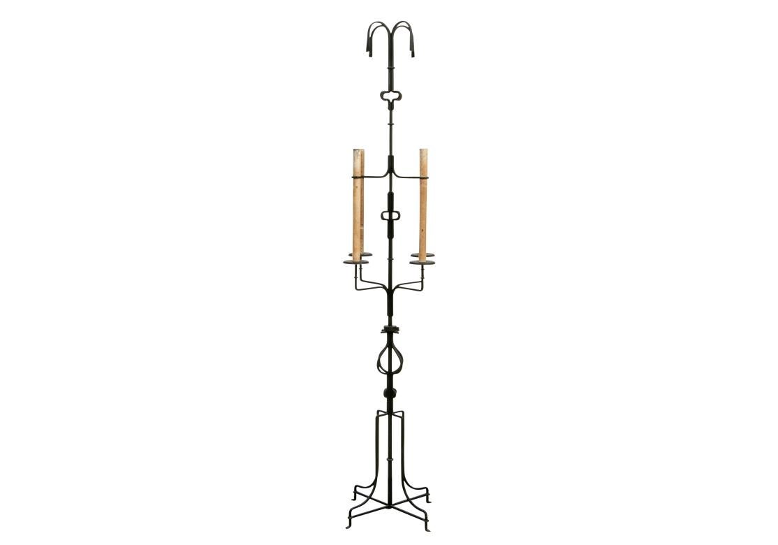 Designed by Tommi Parzinger for Parzinger Originals in the 1950’s. A tall electrified iron torchiere with four faux candles in antiqued finish with a marvelous fountain like top finial.  The standard with shaped details on the top, middle and lower