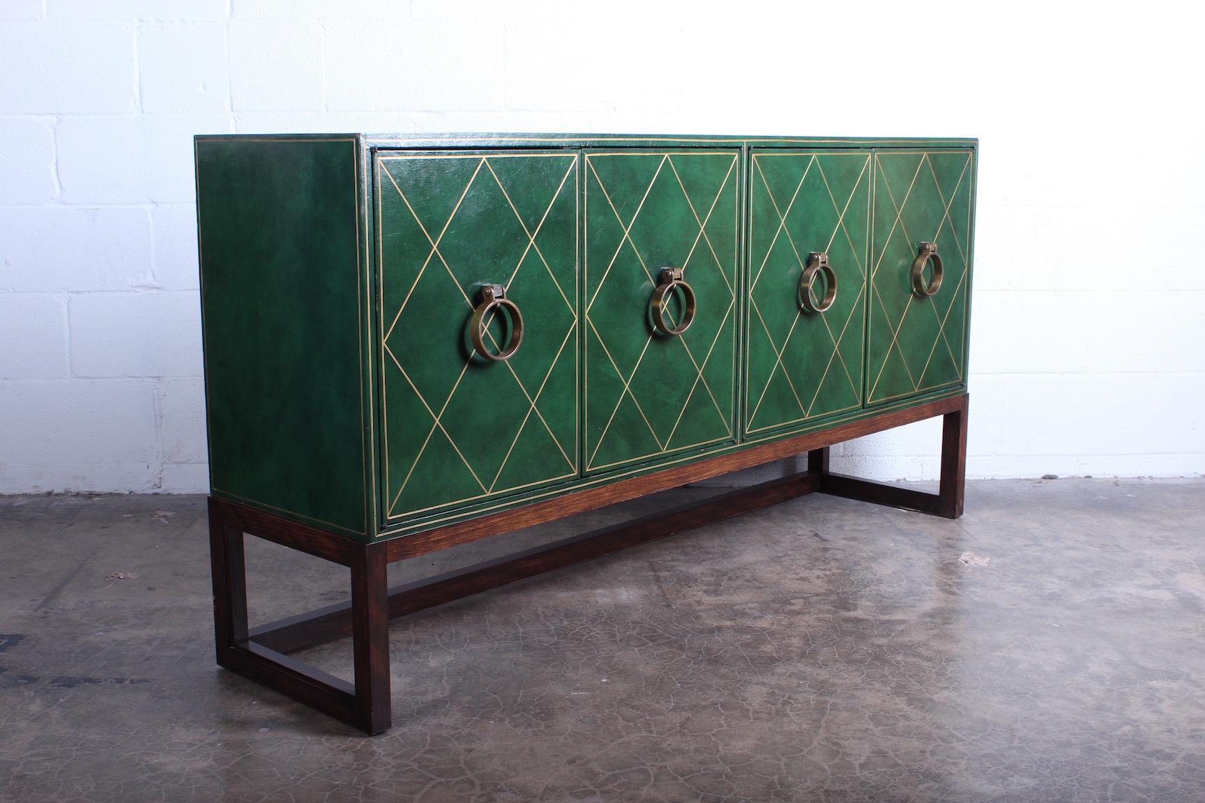 A leather clad cabinet with bronze hardware and mahogany base. Designed by Tommi Parzinger for Parzinger originals.