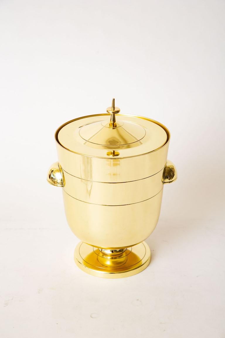 This iconic Classic Mid-Century Modern lidded Tommi Parzinger brass ice bucket or champagne bucket is from the 50's. It has been newly polished and lacquered to prevent tarnishing. It retains the original mercury glass insert. This is a timeless and