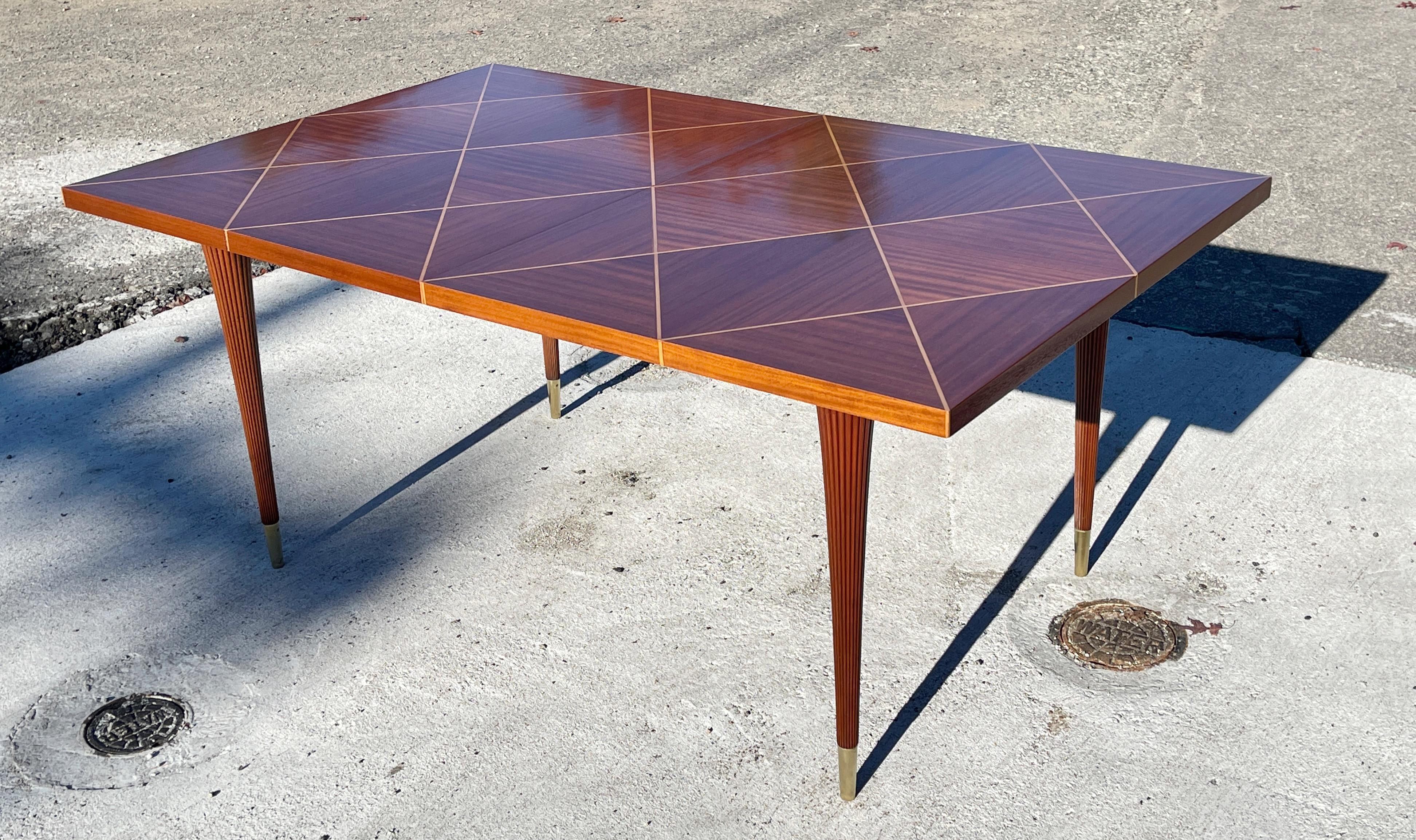 Jaw-droppingly gorgeous extendable dining table designed by Tommi Parzinger for Charak Modern circa 1953. 
Mahogany diamond box parquetry with alternating grain direction and satinwood inlay which almost looks like brass.
Elegant tapered fluted