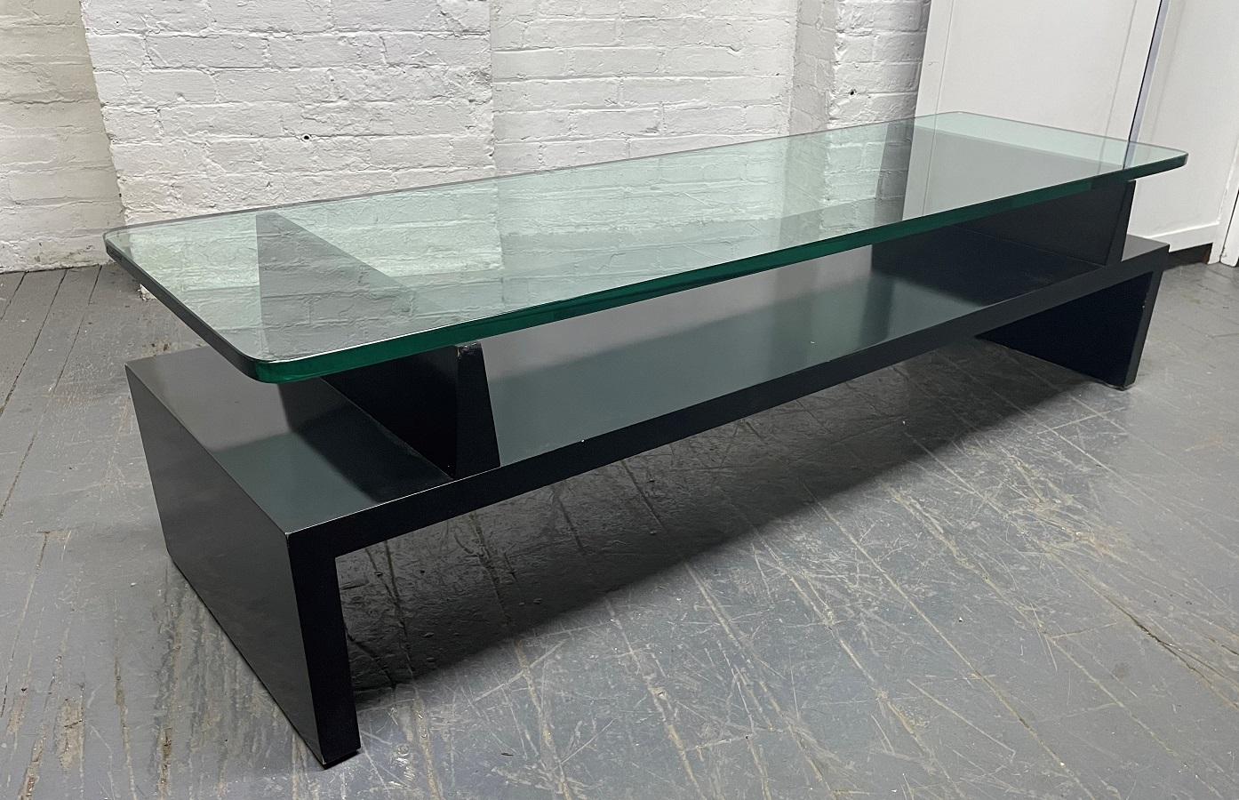 Tommi Parzinger Originals coffee table. The table has a black lacquered wood base, a glass top and stamped Parzinger Originals to the underside. 

  