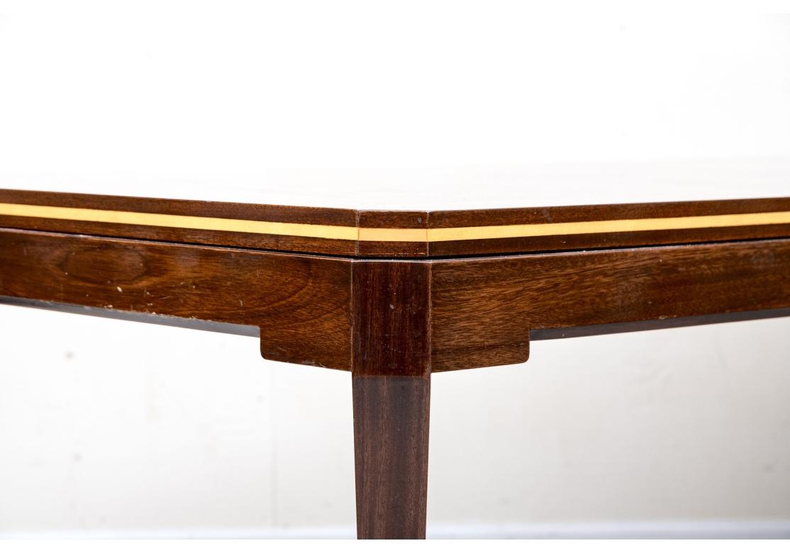 Le design classique et exquis du milieu du siècle de Parzinger Originals. Une table de salle à manger en acajou finement construite avec des coins inclinés et de fines bandes de bois doublement pâle sur le plateau et ses bords. Deux feuilles sont