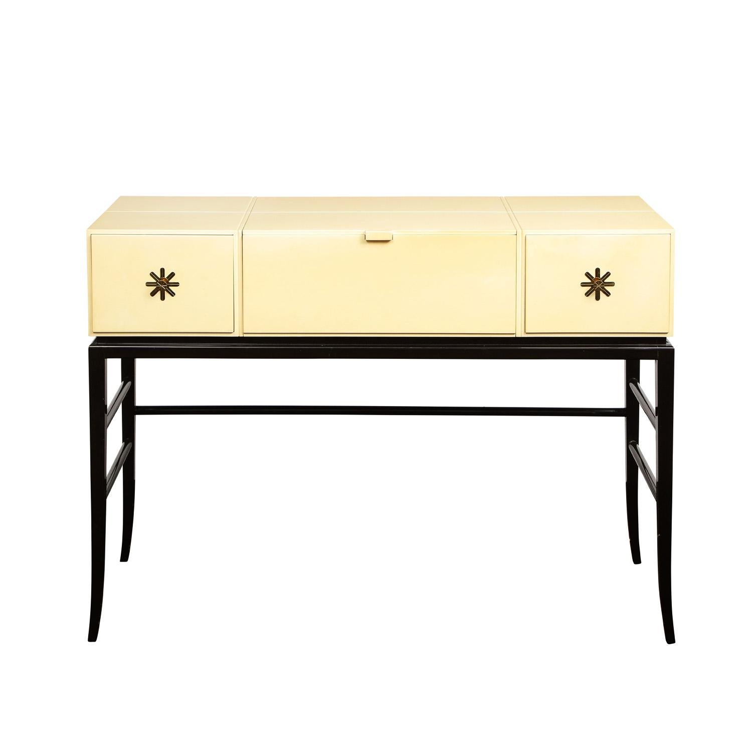 Elegant rare illuminated vanity with lift up top with concealed mirror and light underneath and drop down front, in ivory and black lacquer, with iconic etched brass pulls on drawers by Tommi Parzinger for Parzinger Originals, American 1960's. This
