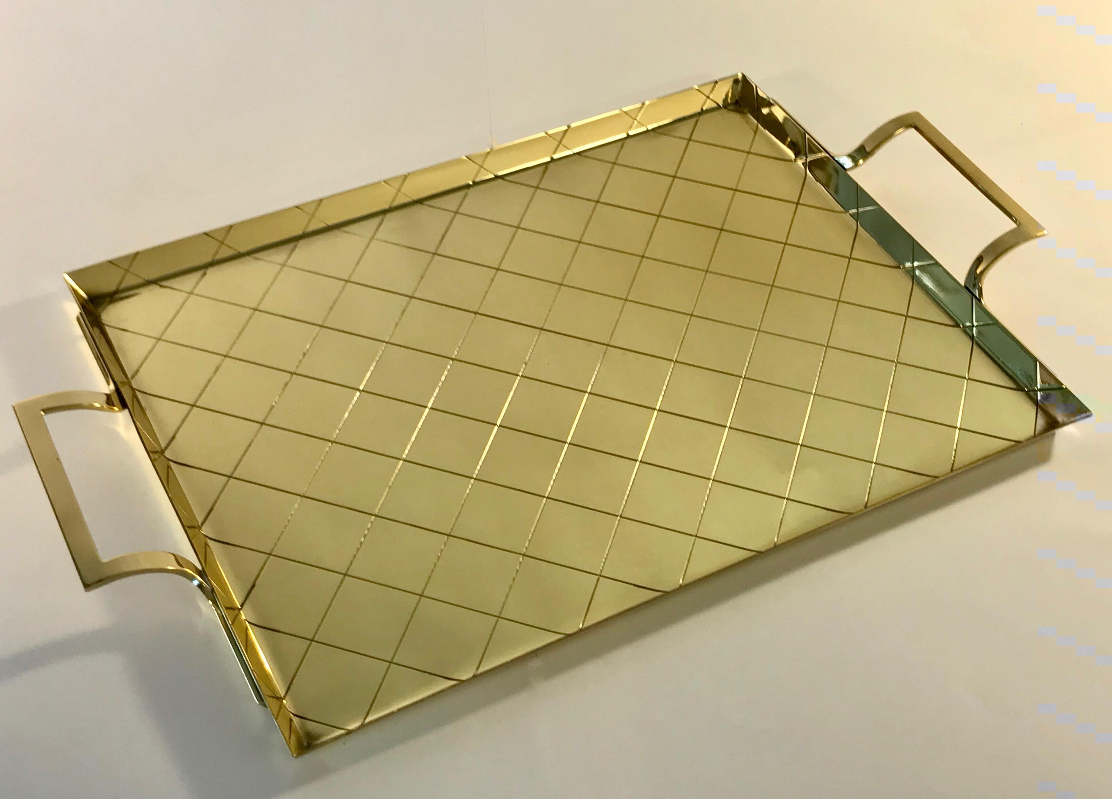 Rectangular brass tray with upswept brass handles and incised diamond or crosshatch pattern designed by Tommi Parzinger and manufactured in New York by Dorlyn Silversmiths.

Measures: 11