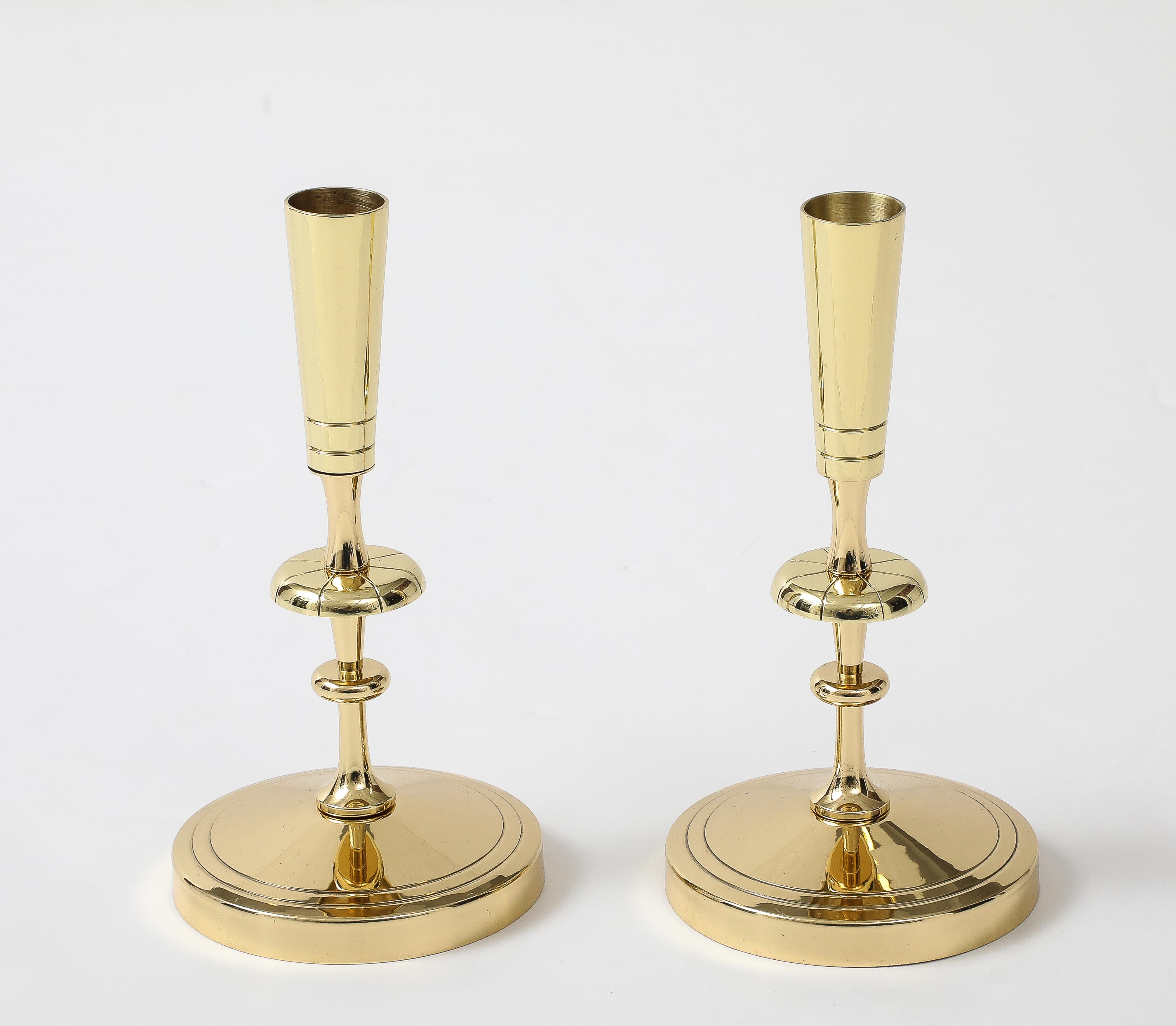 Pair of classically styled brass candlesticks with round bases and a tapering candle holder. Designed by Tommi Parzinger, 1960s. Professionally polished and lacquered.