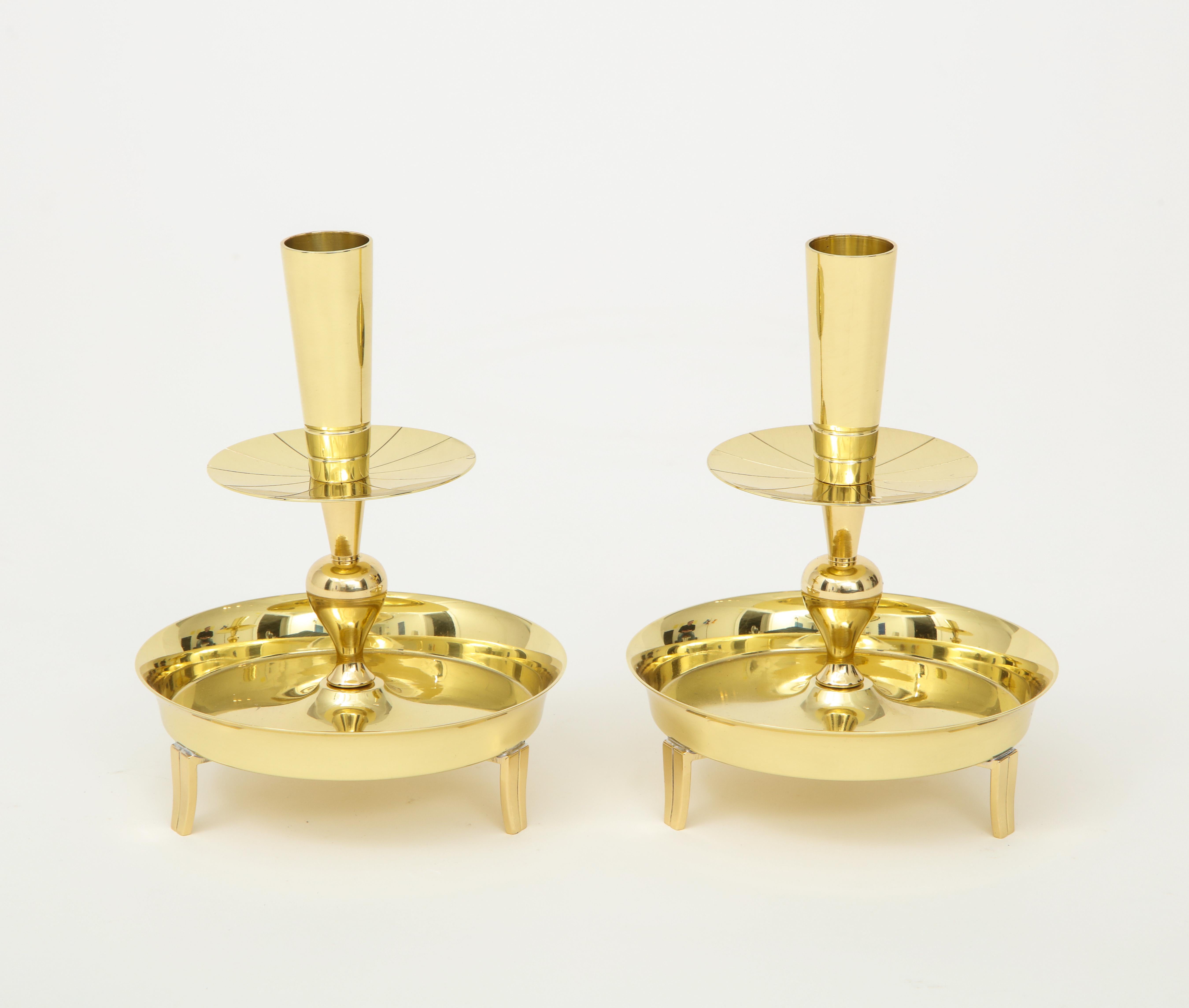 Pair of brass candlesticks with a circular base with 3 fluted legs and a tapering candleholder. Stamped on bottom. Professionally polished and lacquered.