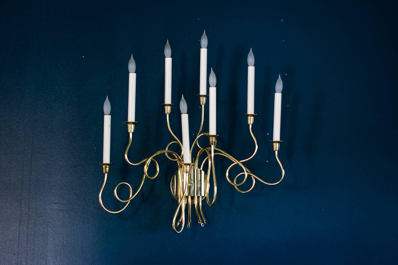 Wall sconce in the manner of Tommi Parzinger, 1950s, in asymmetrically looped brass with eight candelabra lights.