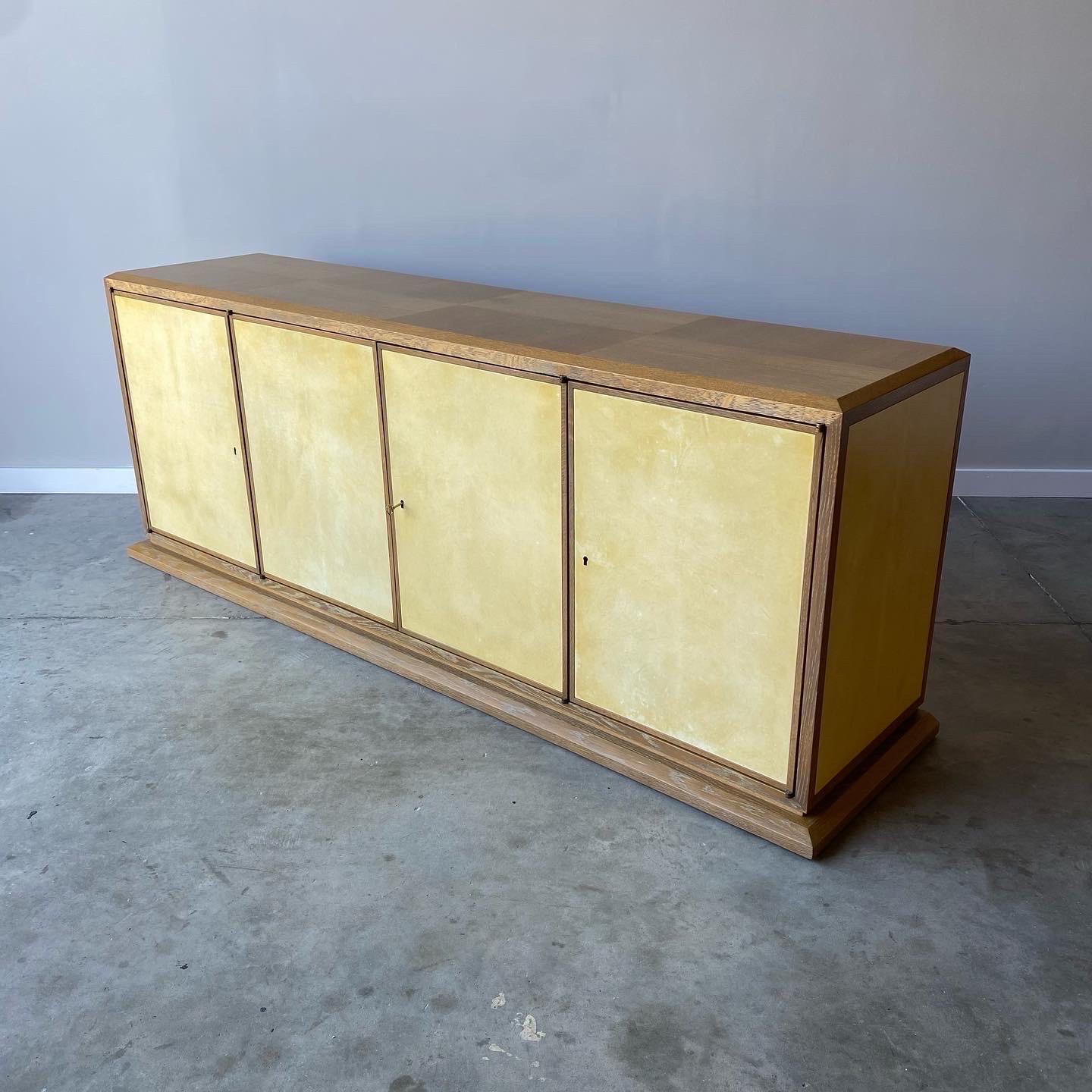 White oak and goatskin are the highlights to this massive credenza. The oak has a beautiful cerused finish with goatskin parchment panel inserts. This cabinet looks to be a Tommi Parzinger design for Charak Modern but is unmarked

This piece dates