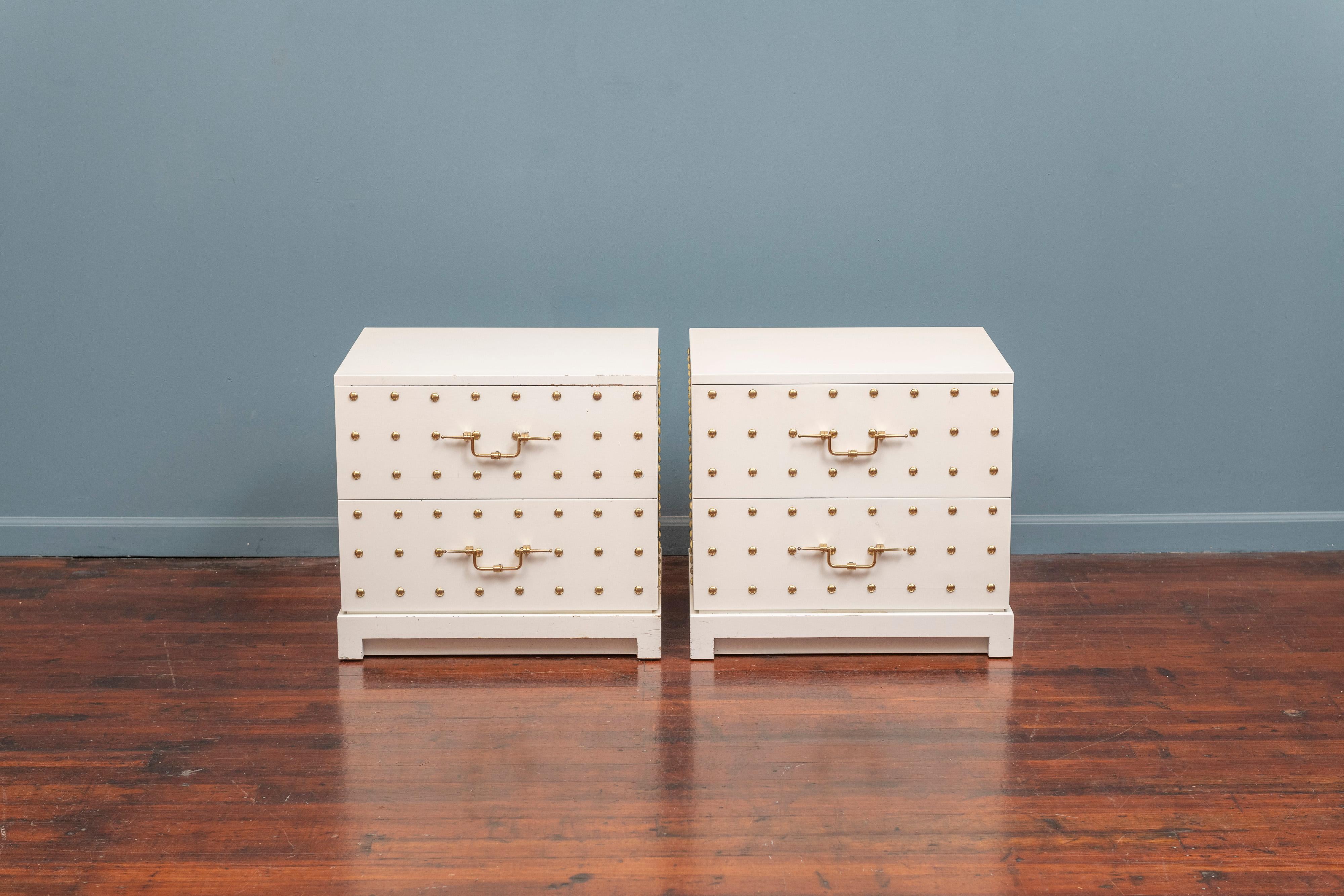 Tommi Parzinger pair of two-drawer white lacquered dressers inset with brass studs and original solid brass decorative handles. 
This is a stunning example of Tommi Parzinger for Parzinger Originals in good original condition with signs of wear and