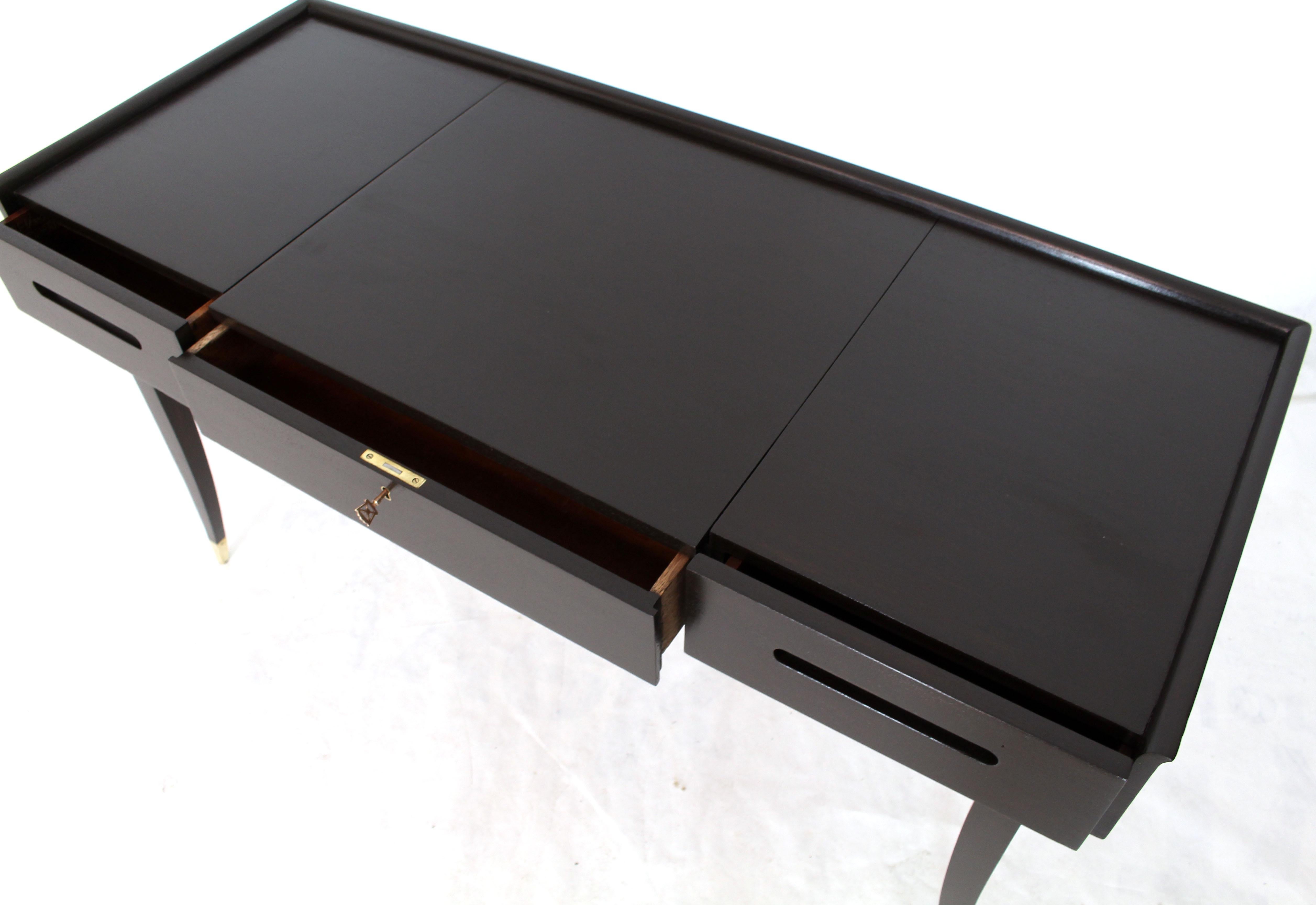 Mid-Century Modern solid mahogany writing table entry console table desk. All solid mahogany construction. Pull-out desk top with small secret compartment. Dark chocolate near ebonized finish. Standing on beautiful tapered saber legs with brass