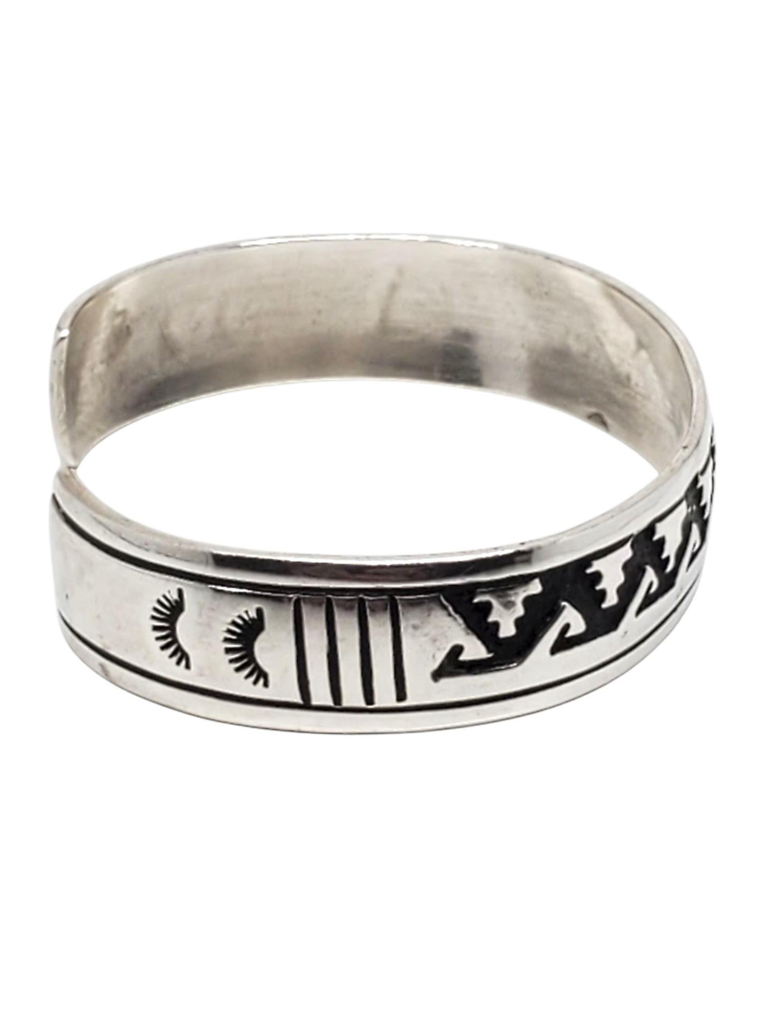 Tommy Singer Bracciale in argento Sterling dei Nativi Americani -

Questo audace bracciale artigianale dei nativi americani è realizzato in argento massiccio e presenta una profonda lavorazione geometrica con accenti ossidati, firmata T.