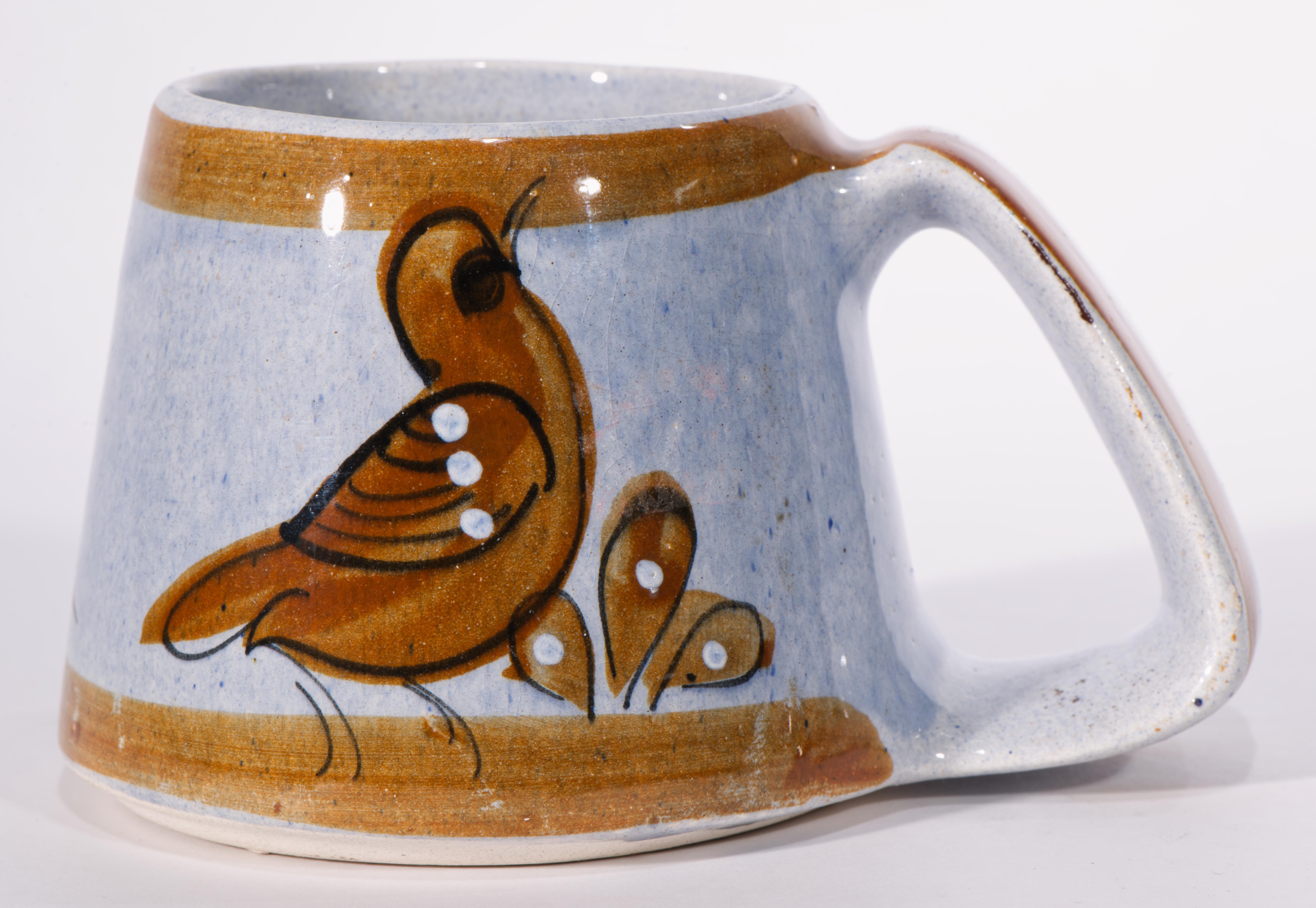 Cette paire de tasses ou de gobelets en céramique de forme trapézoïdale présente un décor de style Folk Art avec de charmants oiseaux sur des branches sur la face avant et des motifs abstraits de branches et de feuilles sur les faces arrière des