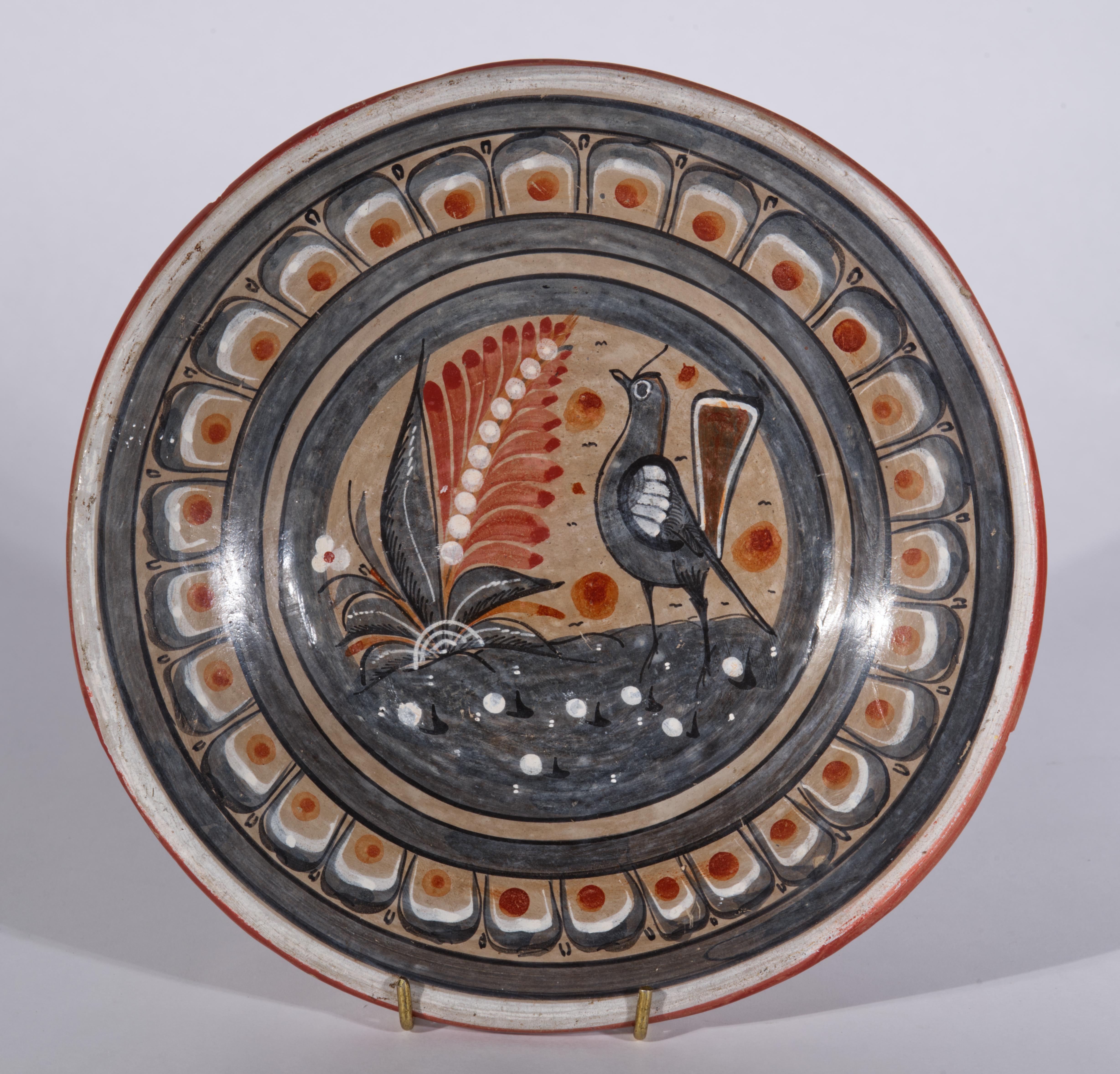  Il piatto o vassoio decorativo da parete in ceramica è dipinto a mano in stile Folk Art con il motivo affascinante e dettagliato di un uccello accanto a un grande fiore. Il  Il motivo, dipinto in grigio blu, bianco sporco e marrone moka su sfondo