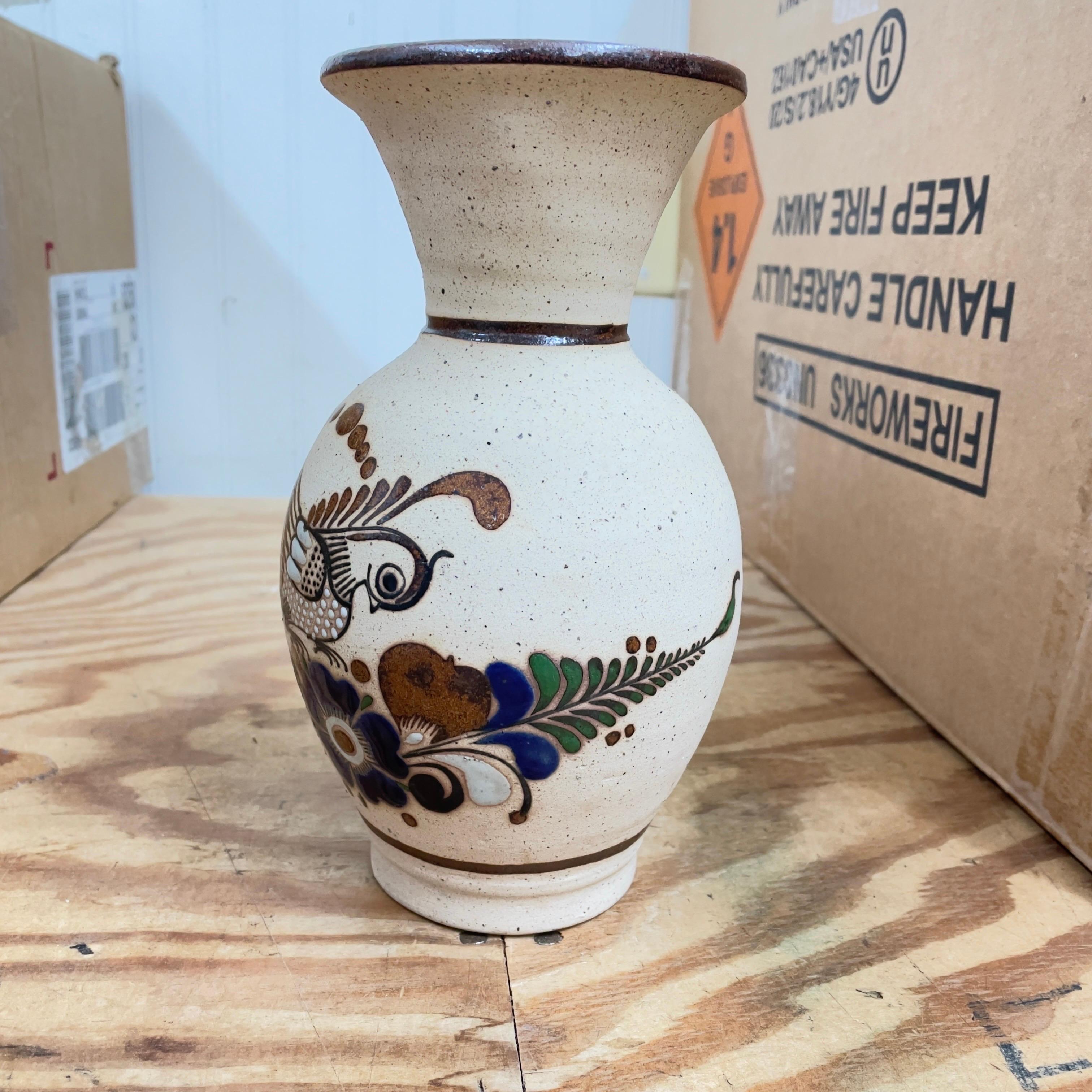 Une belle poterie d'art populaire mexicain Tonala avec un oiseau avec des points blancs et une fleur multicolore sur la surface. Vase de taille décente et pratique. Sa surface naturelle de couleur terre se marie bien avec de nombreux types de décors