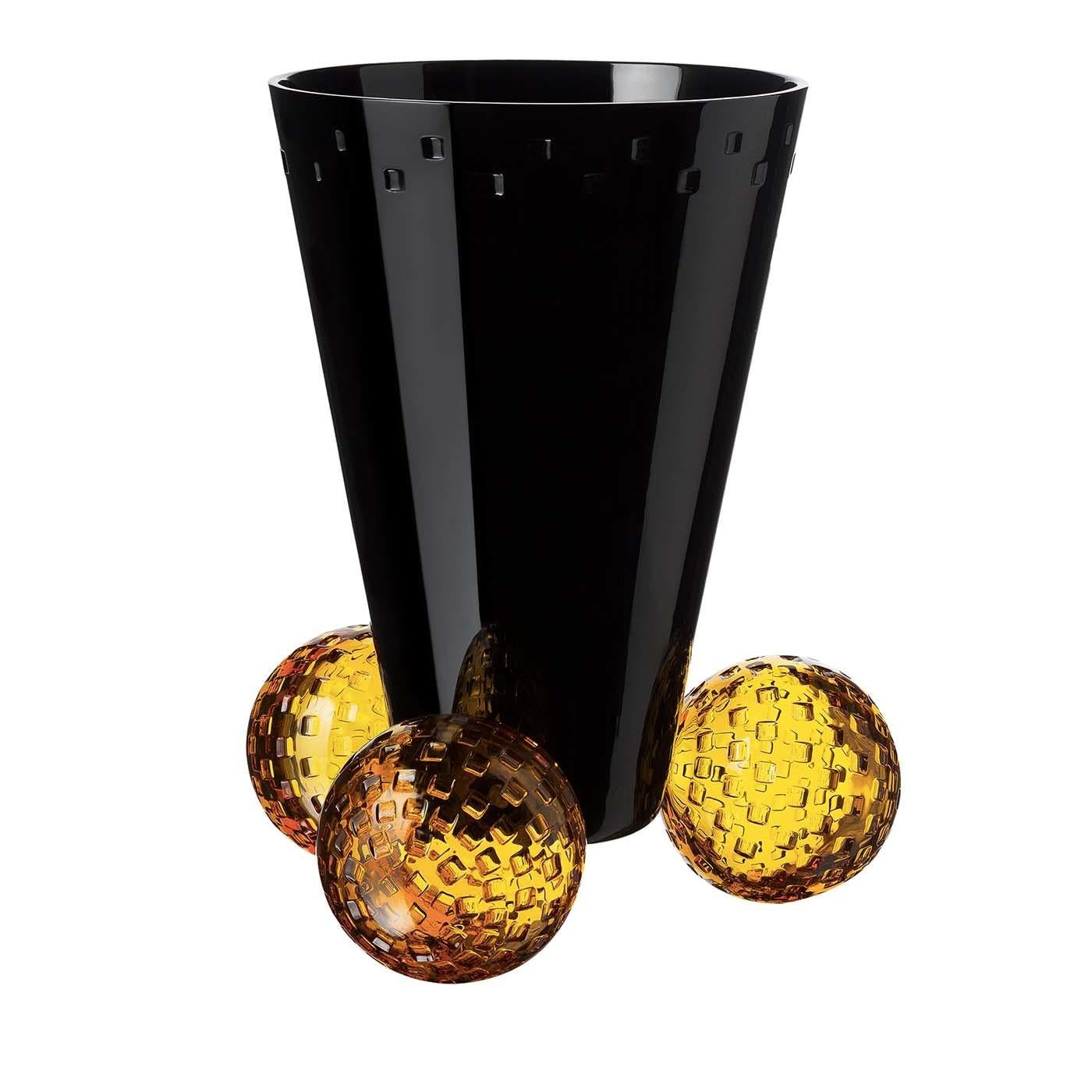 This stunning crystal vase is part of the Acrobat collection. Its conical body in striking black is supported by a base made up of three amber-colored balls. The contrast between the two colors is enriched by a striking texture that covers the