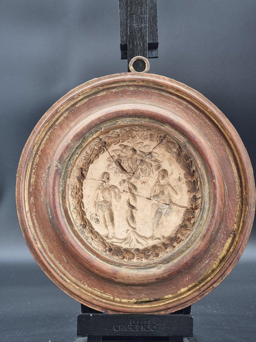 Tondo ligneo tornito da un unico pezzo di noce, con al centro un raro calco in stucco raffigurante la scena biblica dell’Albero della Vita con Adamo, Eva e il serpente. L’opera, databile alla metà del Seicento, presenta una cornice a profilo