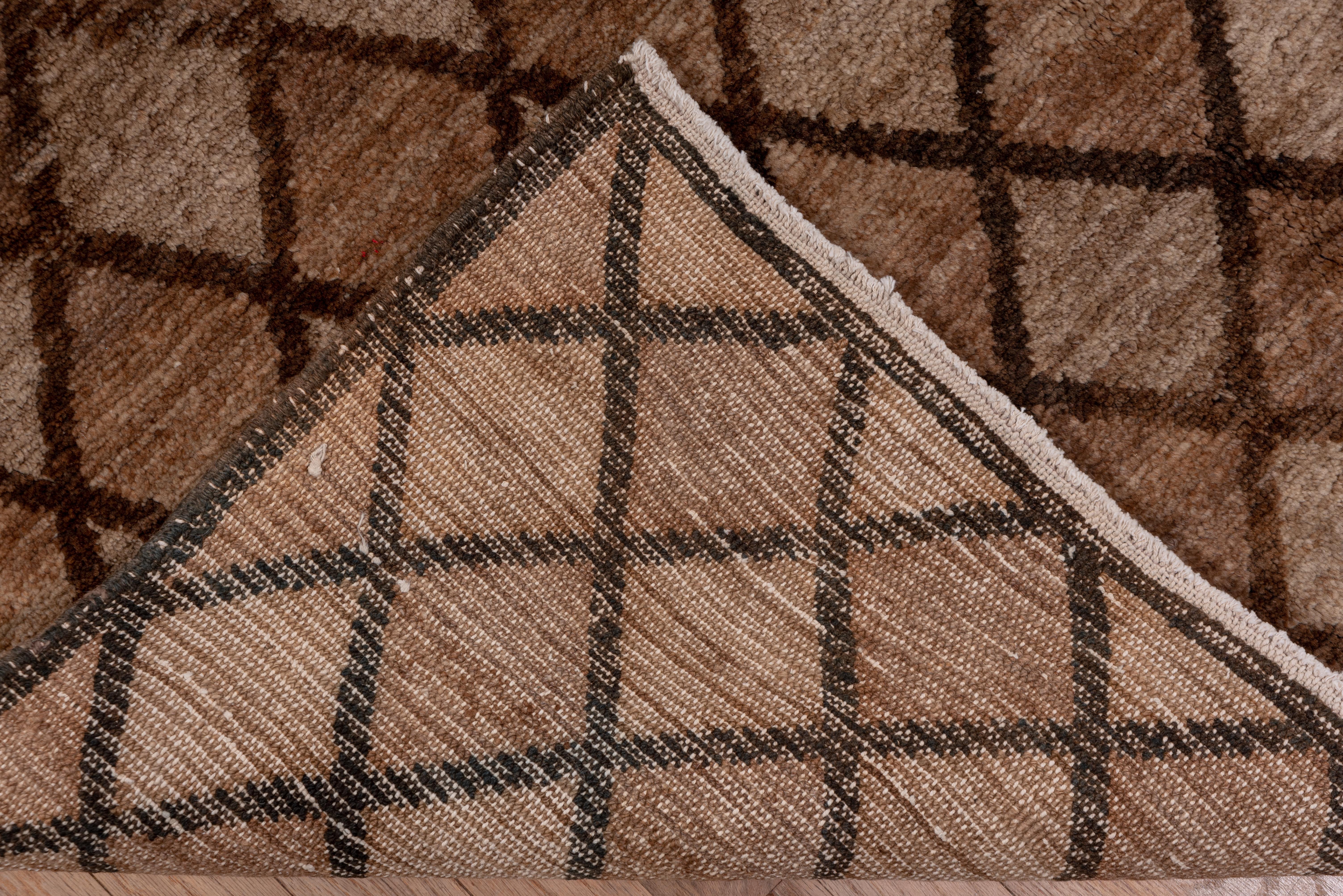 This vintage East Anatolian longish carpet shows a total lozenge pattern in shades of ecru-tan and abrashed light brown in a brick lattice, with no borders. Abrash lines show the rustic origins. This was not a factory carpet, but a real village