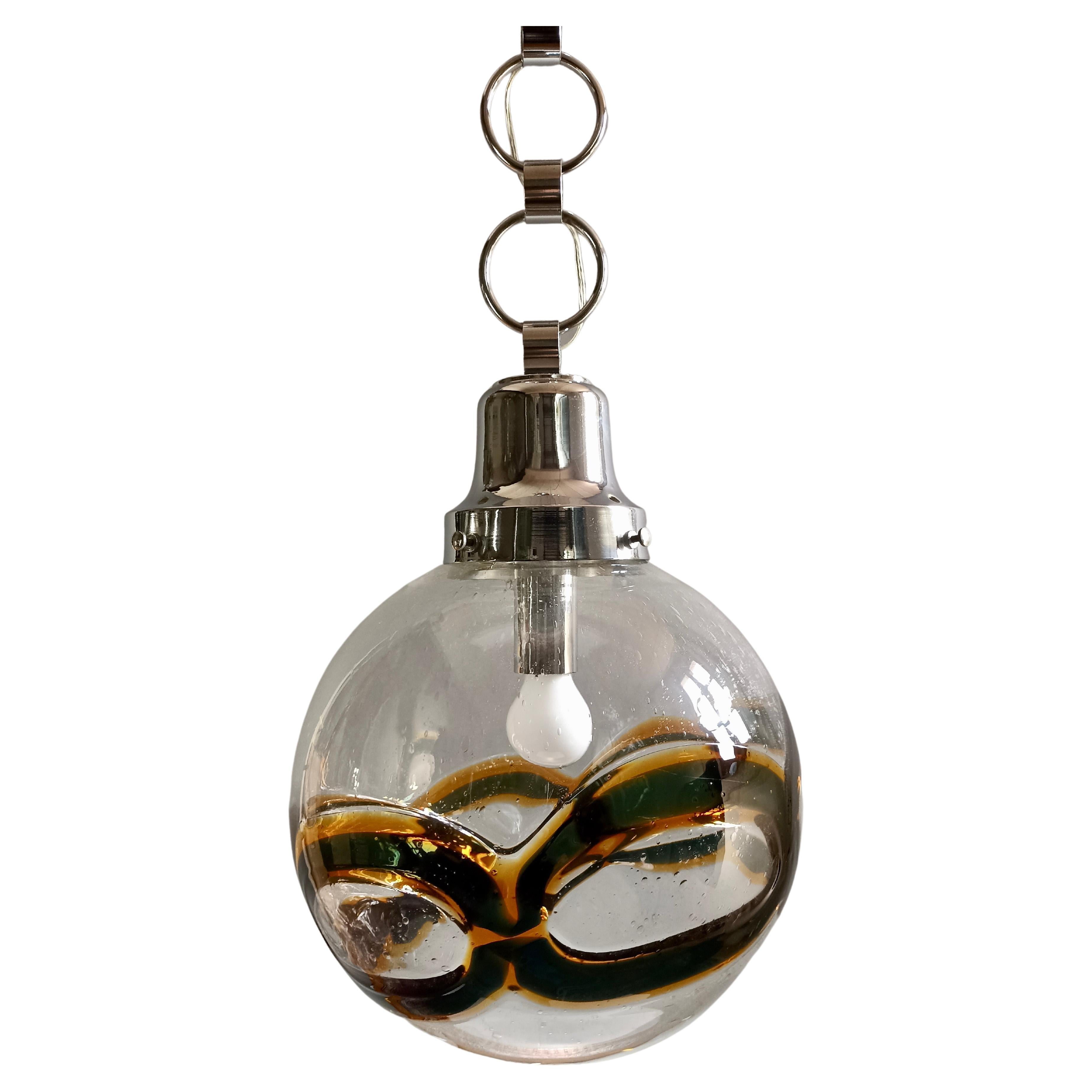 Fascinante et rare grande lampe suspendue en verre de Murano attribuable à Toni Zuccheri, datant des années 1960/70.
L'abat-jour en verre soufflé à la bouche est transparent et présente un fin travail de Pulegoso ainsi qu'une bande irrégulière de