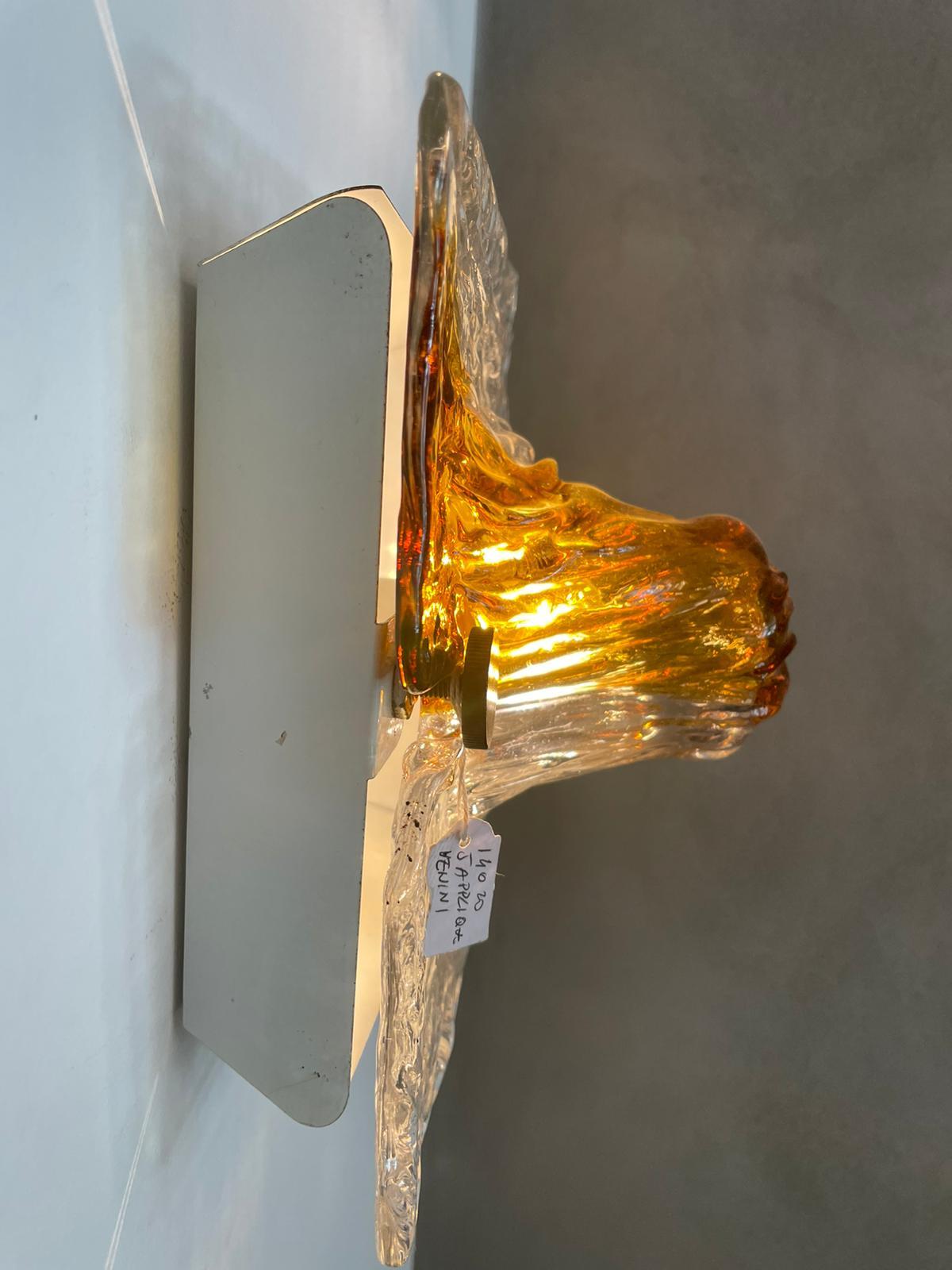 Pair of wall lights desiged by Toni Zuccheri and manufactured by Venini Italy, 1960s
Hand-blown Murano glass with amber tones, white lacquered frames, brass screws.
Excellent vintage patina.
The electrical system has been overhauled.

 