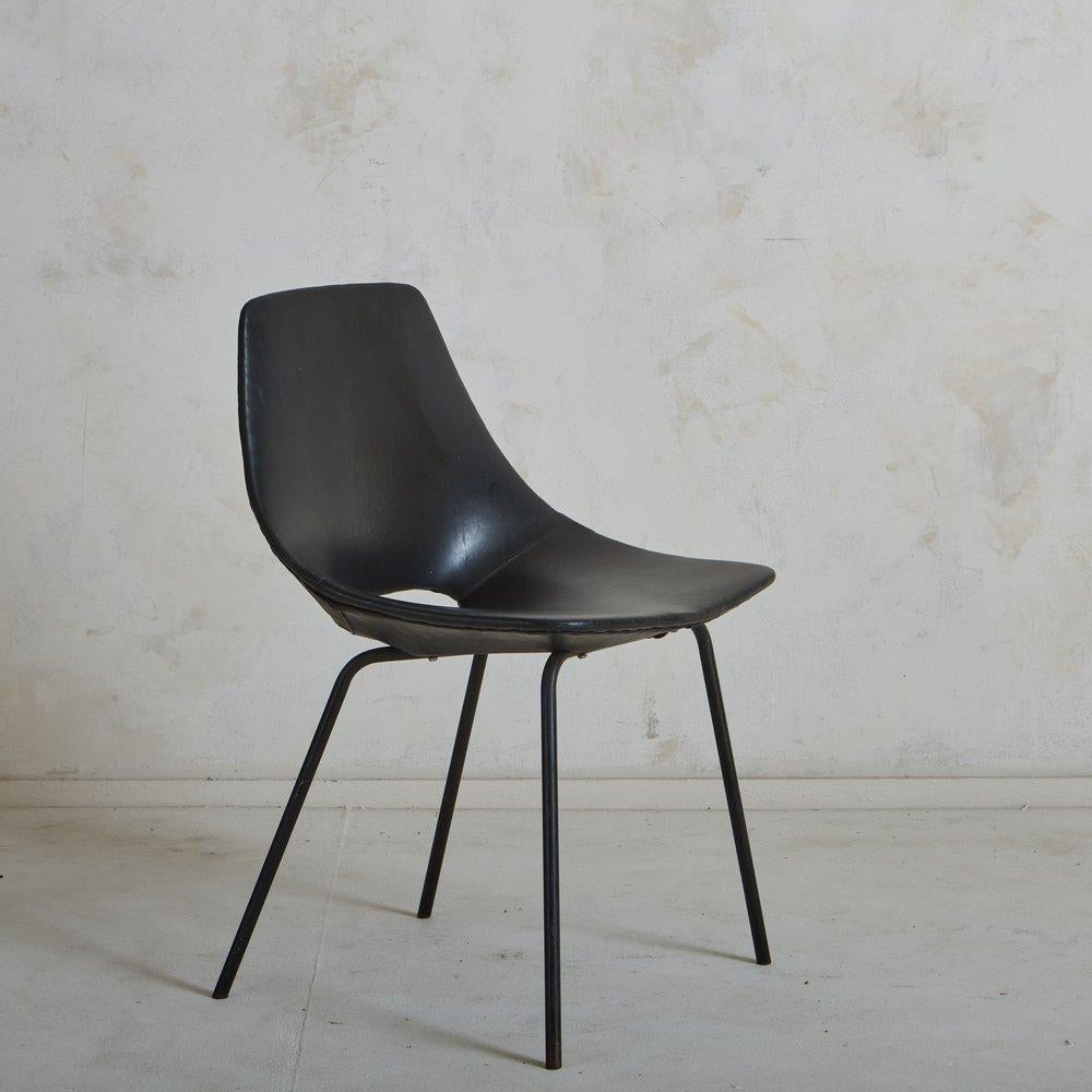 A ‘Tonneau’ chair designed by Pierre Guariche for Steiner in the 1950s. This chair has a curved seat with an oval cutout detail in handsome stitched black leather. It has four angled, tubular enameled iron legs. Retains ‘Steiner’ label under seat.