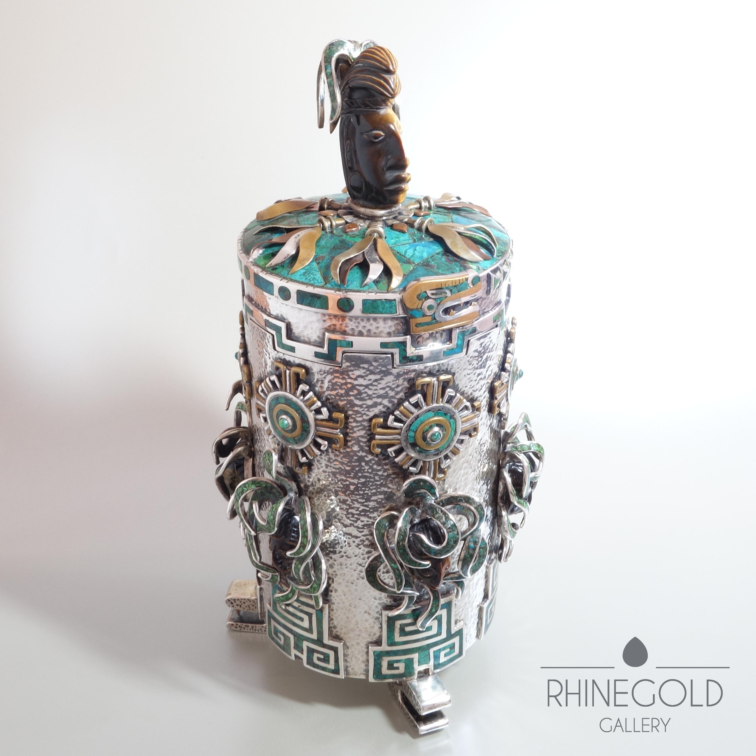 Tono Mexican Aztec Maya Motif Precious Stone Silver Tea Caddy Box
Sterling silver, brass, copper, tiger’s eye, azurite, chrysocolla
Height 23 cm (approx. 9”), diameter 12.5 cm (approx. 4 ¾”)
Weight 1,049 grams (= approx.  2.3 lbs)
Marks: ‘Toňo 