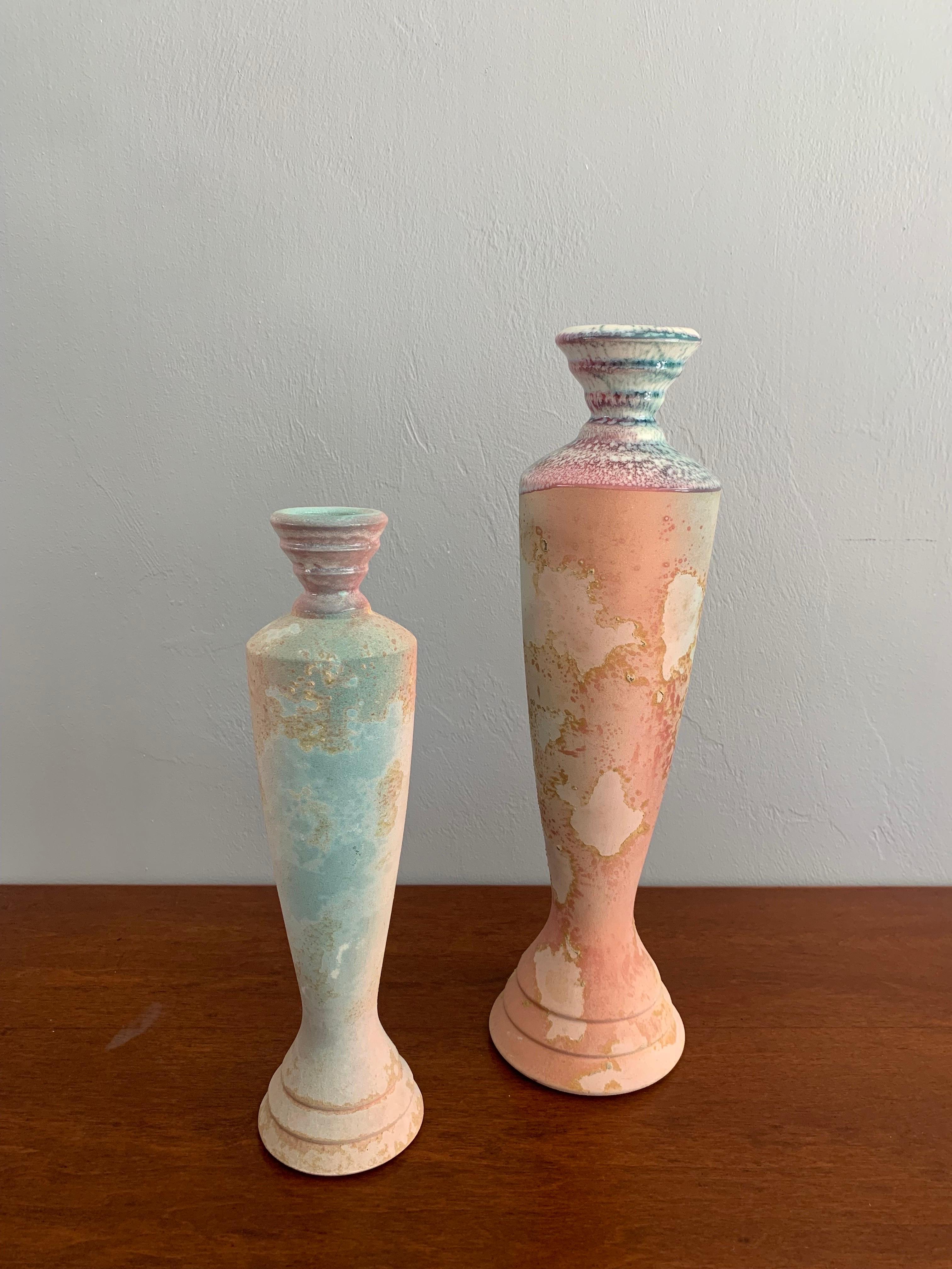 A beautiful set of multi-colored raku candlesticks. Done in the traditional raku style by famed American artist Tony Evans. The texture of the Raku in this almost vapor wave color scheme creates an almost map like pattern across each candlestick.