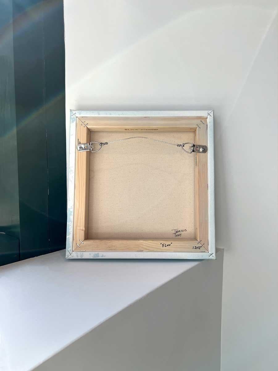 Questo piccolo quadro astratto di Tony Iadicicco è realizzato con pittura a olio su tela avvolta in galleria. Tre linee orizzontali parallele di colore grigio-blu scuro si trovano nella parte superiore della composizione, con il bianco ai lati e tra